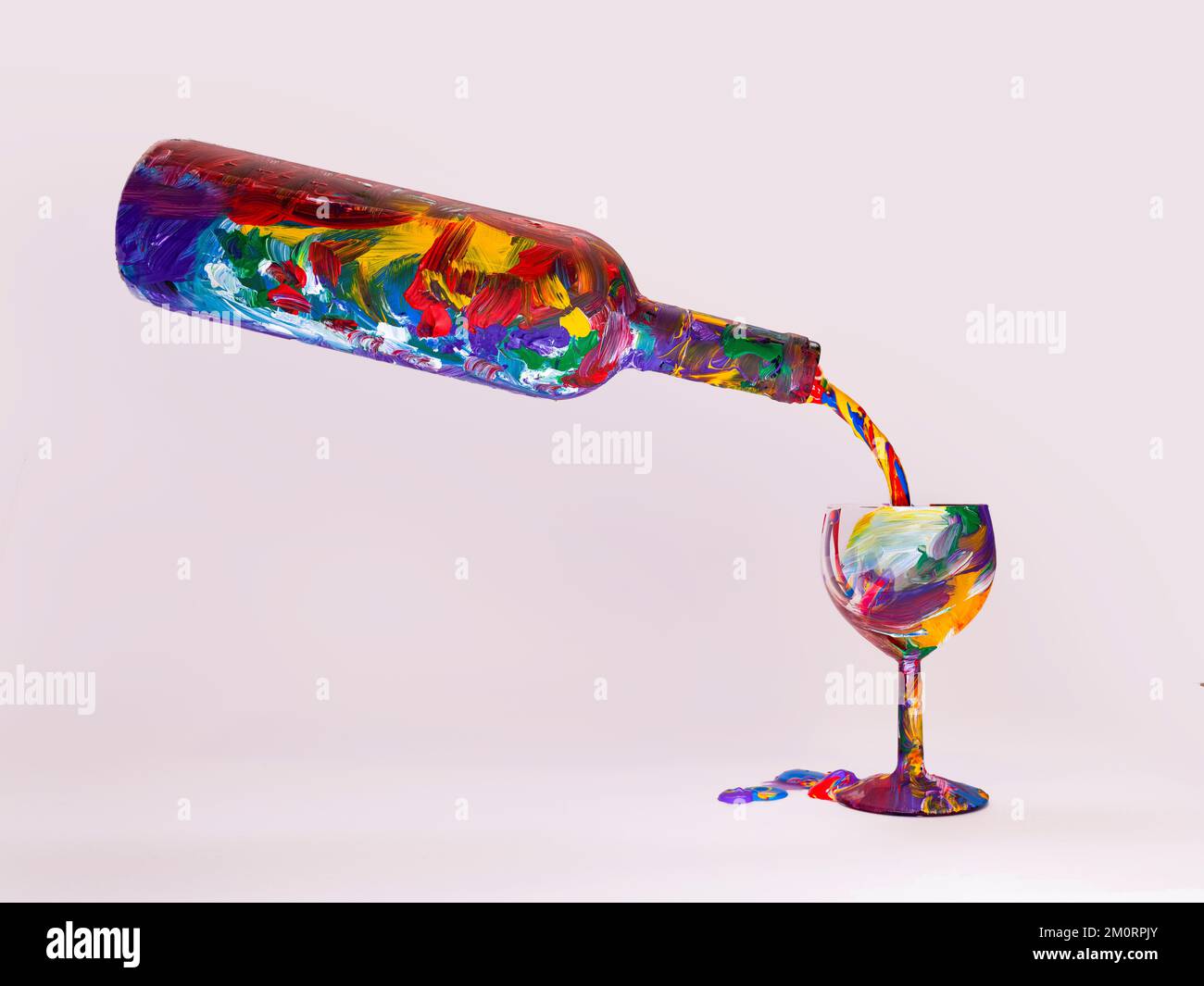 Liquido multicolore versato da una bottiglia dipinta in un bicchiere da vino dipinto Foto Stock