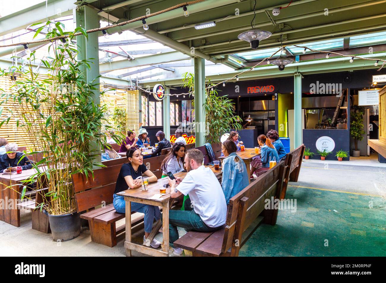 Le persone che si gustano cibo di strada al mercato alimentare di Lalaland Shoreditch, Londra, Regno Unito Foto Stock