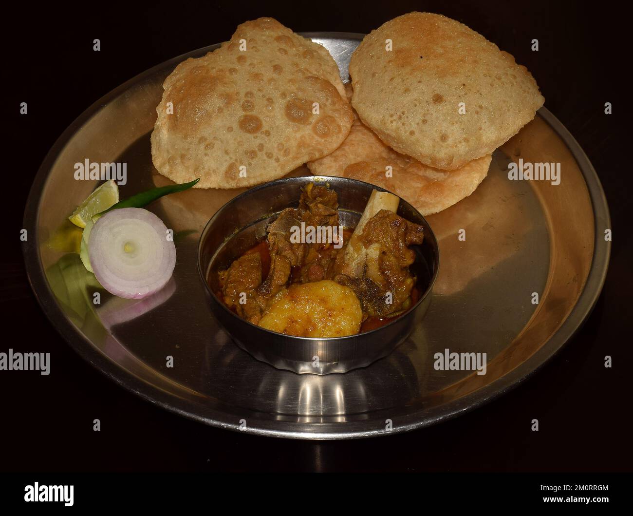 Tradizionale Bengalese piatto Luchi (pane fritto) fatto in casa con kosha Mangsho (curry di montone) servito su un piatto di acciaio Foto Stock