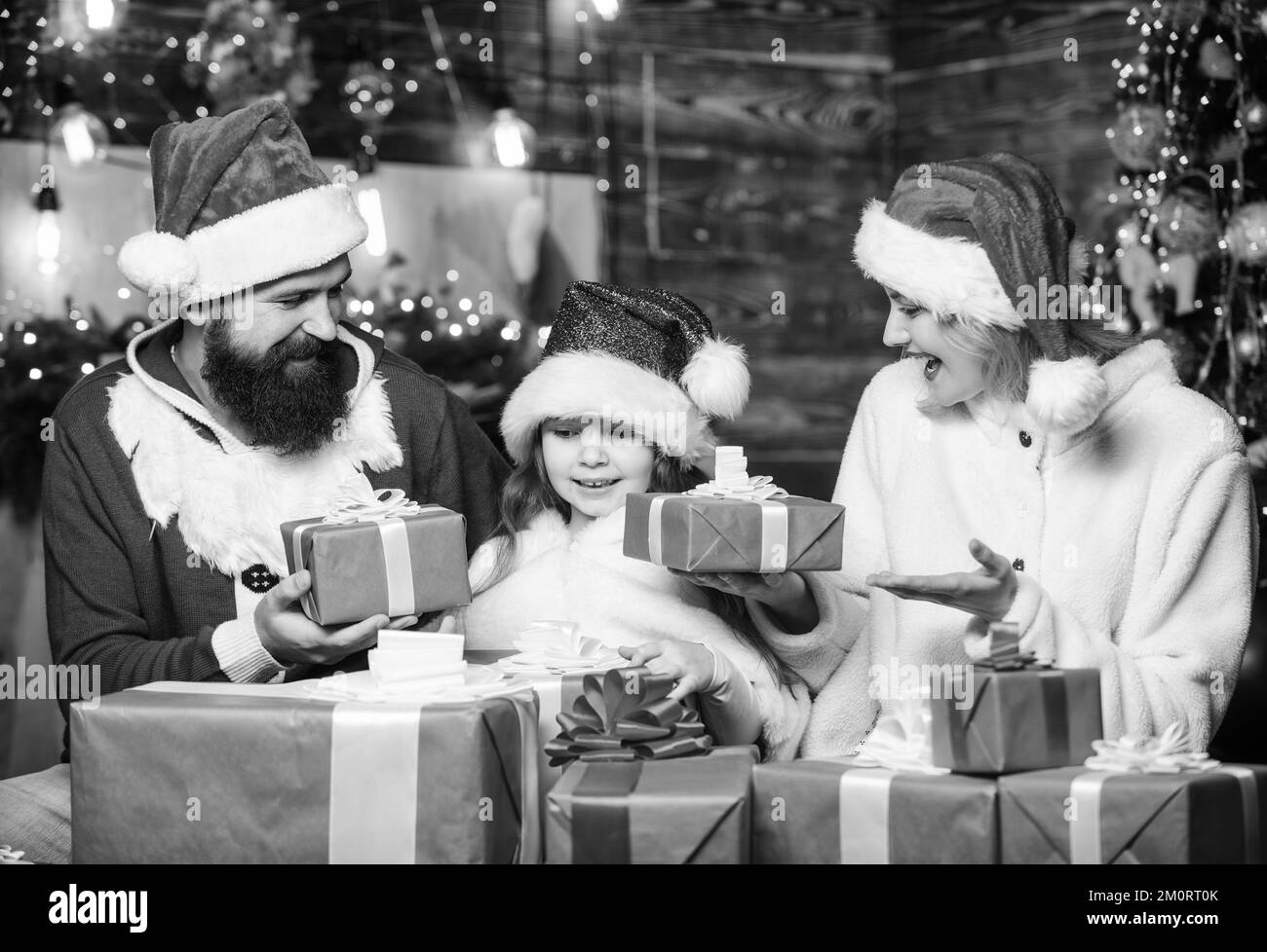 Famiglia felice festeggia il nuovo anno. confezioni regalo di natale. Apri presente. Buon Natale. Padre e madre amano la figlia. bambino piccolo e genitori in babbo natale Foto Stock