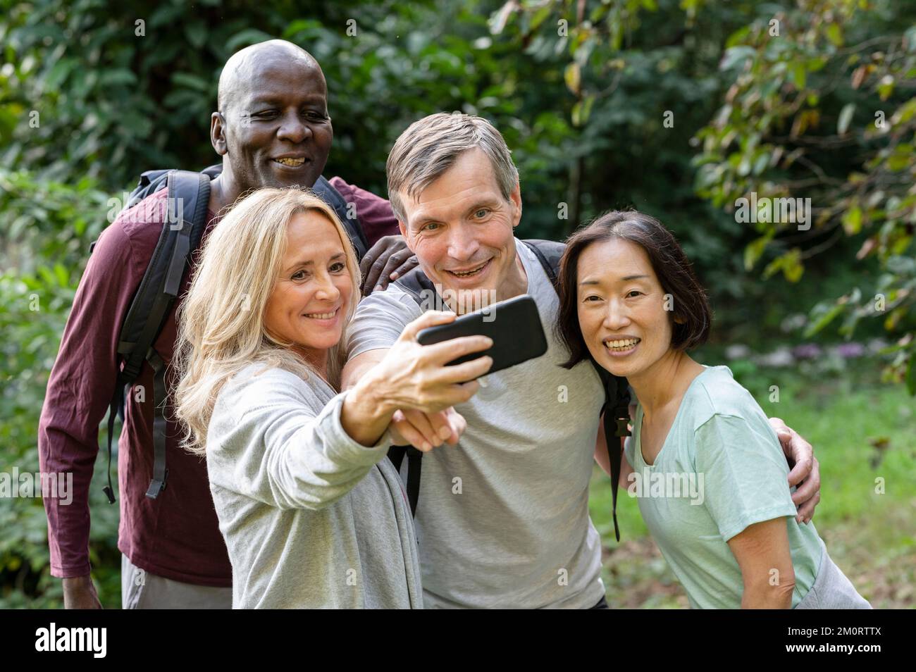 Gruppo eterogeneo di amici di mezza età che fanno un selfie mentre si trovano sui sentieri del backroad Foto Stock