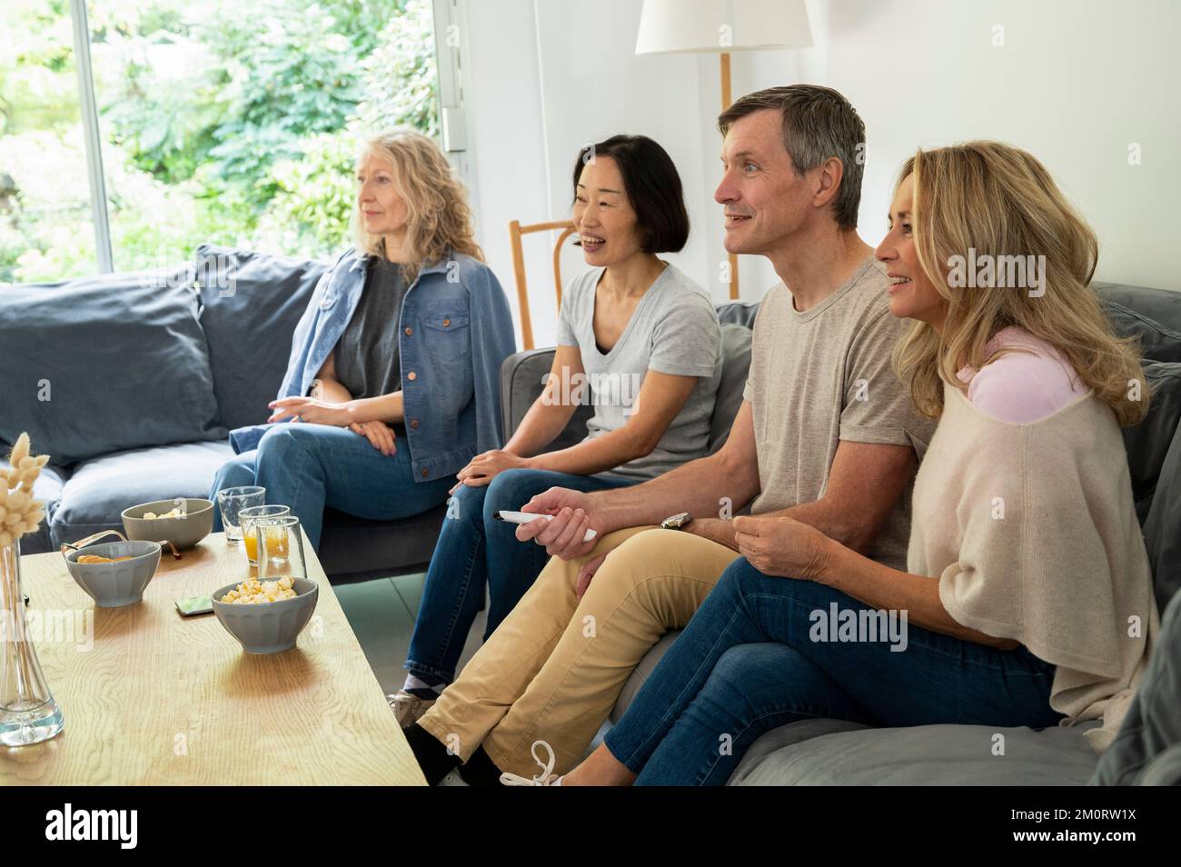 Gruppi di amici diversi seduti sul divano a guardare la TV Foto Stock