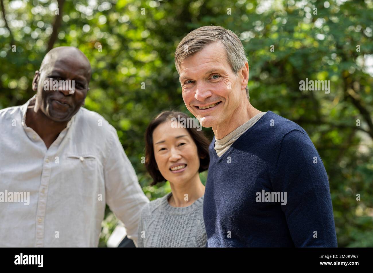Portrait of middle age diverse group of friends gathered at public park Foto Stock
