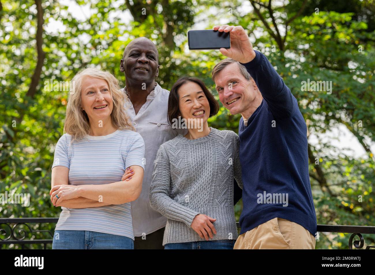 Ritratto di coppie diverse che si divertono mentre scattano un selfie nel parco pubblico Foto Stock
