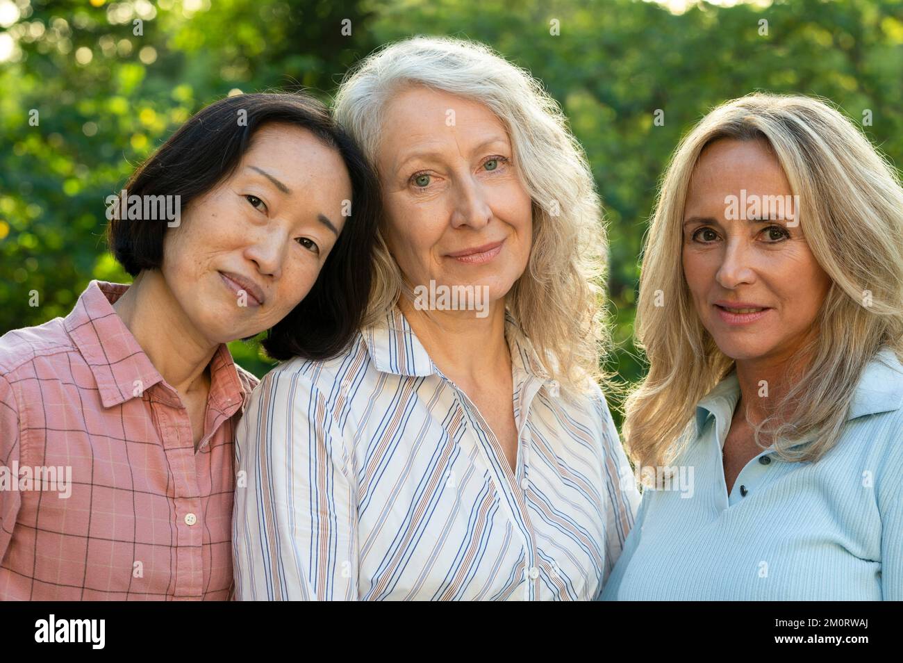 Gruppo di tre donne di mezza età in posa per una foto nel cortile Foto Stock
