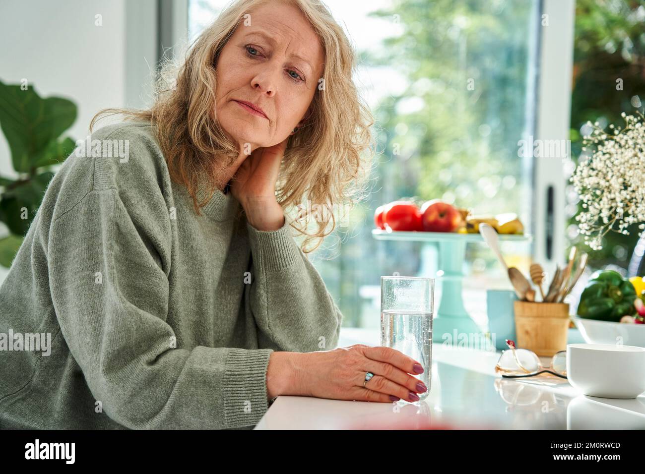 Donna anziana premurosa con mano dietro il collo seduta nella sala da pranzo Foto Stock