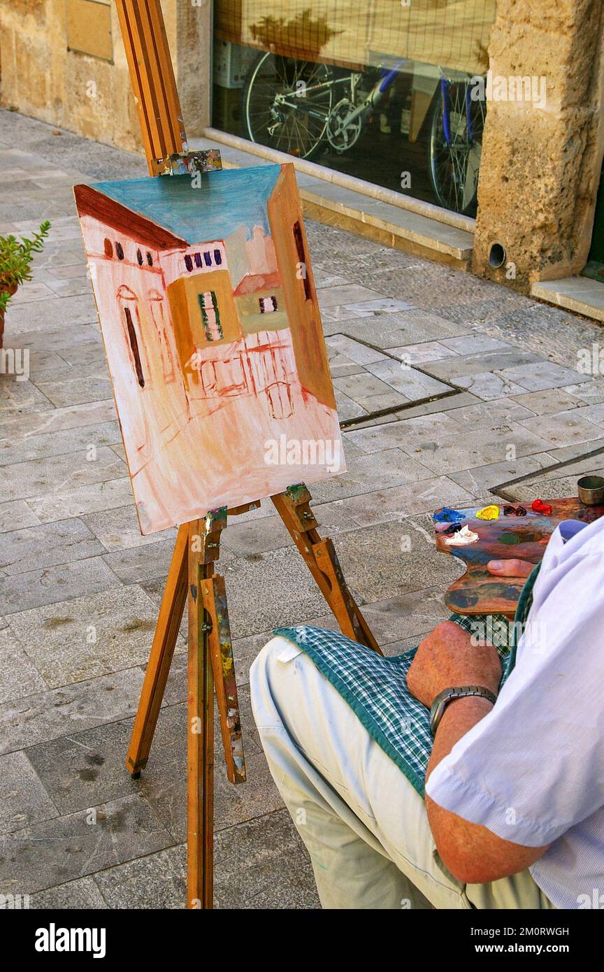 Artista al suo cavalletto dipingendo una scena di strada in estate nel centro storico di Alcudia, Maiorca, Spagna Foto Stock