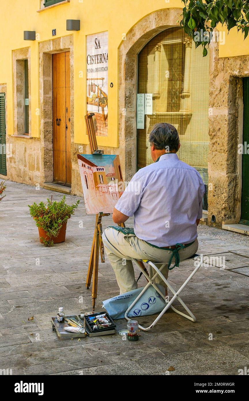 Artista al suo cavalletto dipingendo una scena di strada in estate nel centro storico di Alcudia, Maiorca, Spagna Foto Stock