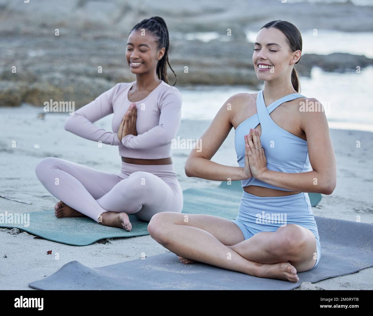 Amici, yoga o meditazione in spiaggia, allenamento e preghiera spirituale, esercizio fisico o sorriso felice all'aperto nella natura. Diversità, pilates o workout in mare Foto Stock