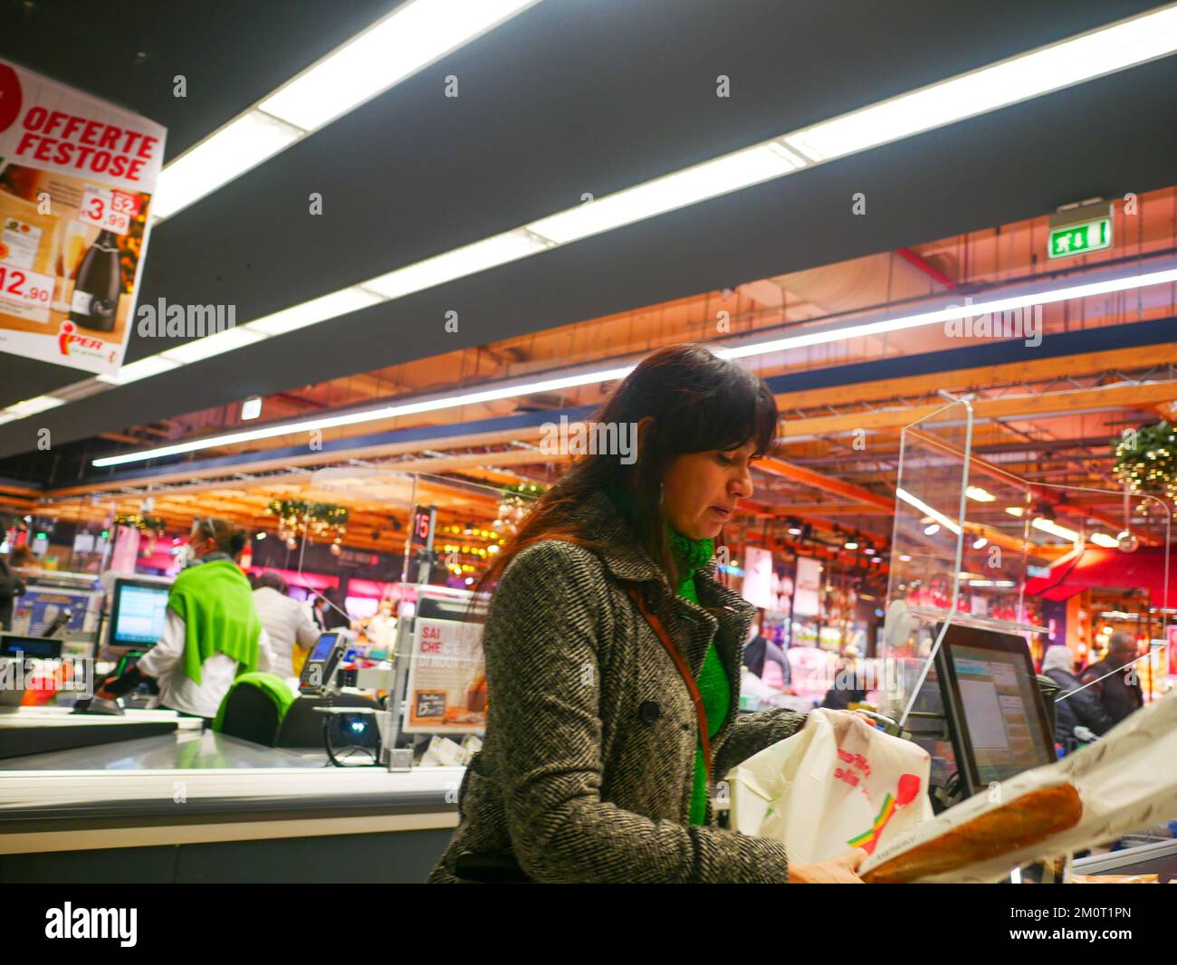 Cremona, Italia - Dicembre 2022 donna ispanica latina al cassiere in supermercato per la spesa Foto Stock