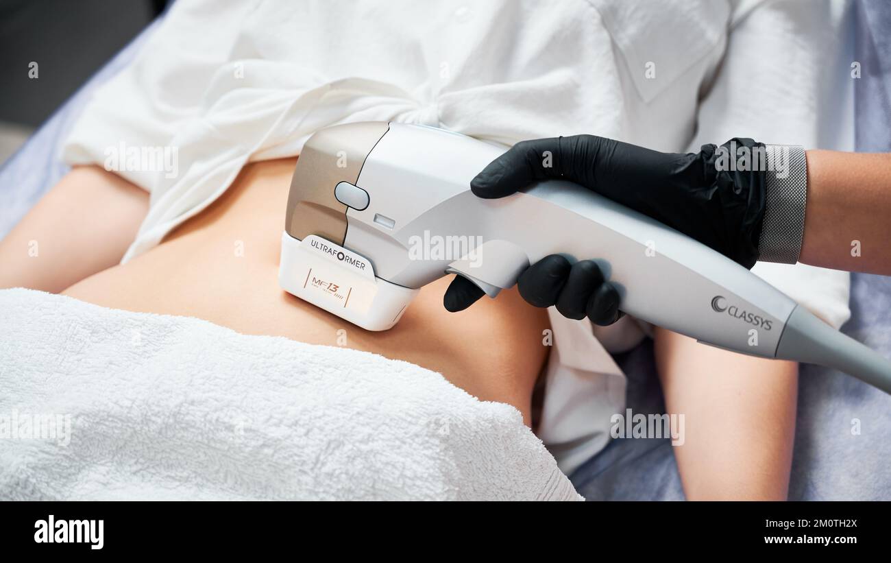 Kyiv, Ucraina - 26 dicembre 2020: Primo piano medico cosmetologo utilizzando ultrasuoni dispositivo Ultraformer durante l'esecuzione della procedura di sollevamento su donna addome. Foto Stock