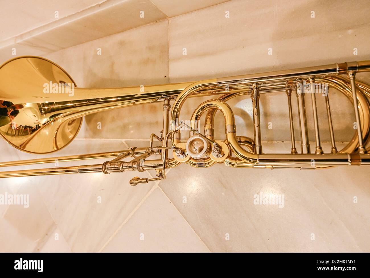 Trombone, strumento musicale ad aria appoggiato sul pavimento in marmo. Foto Stock