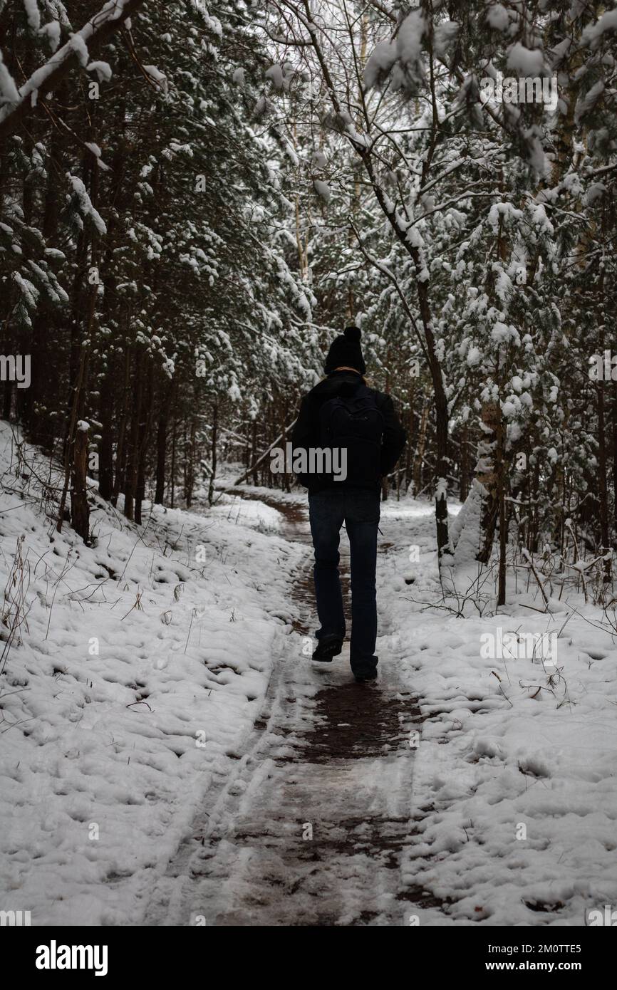 foto di un uomo che cammina lungo un sentiero in una foresta invernale Foto Stock