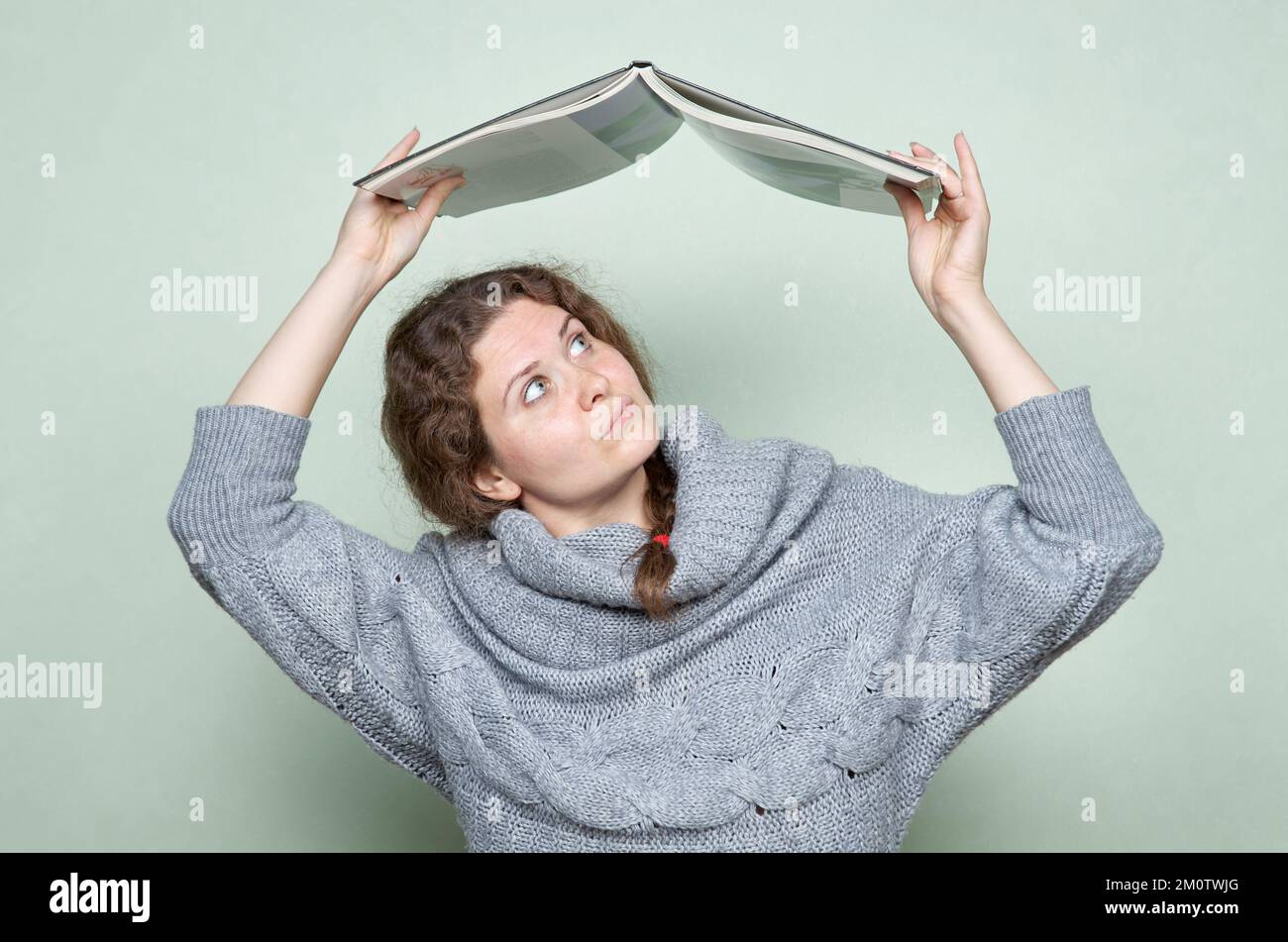 Una donna si nasconde sotto un libro, come sotto un tetto da fattori ostili: Stress, depressione, paura Foto Stock