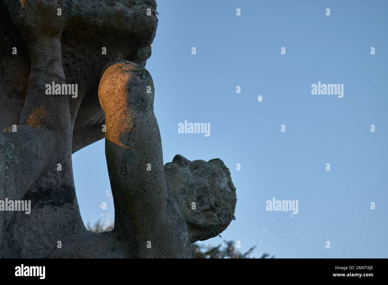 Una statua di pietra con la luna sullo sfondo Foto Stock