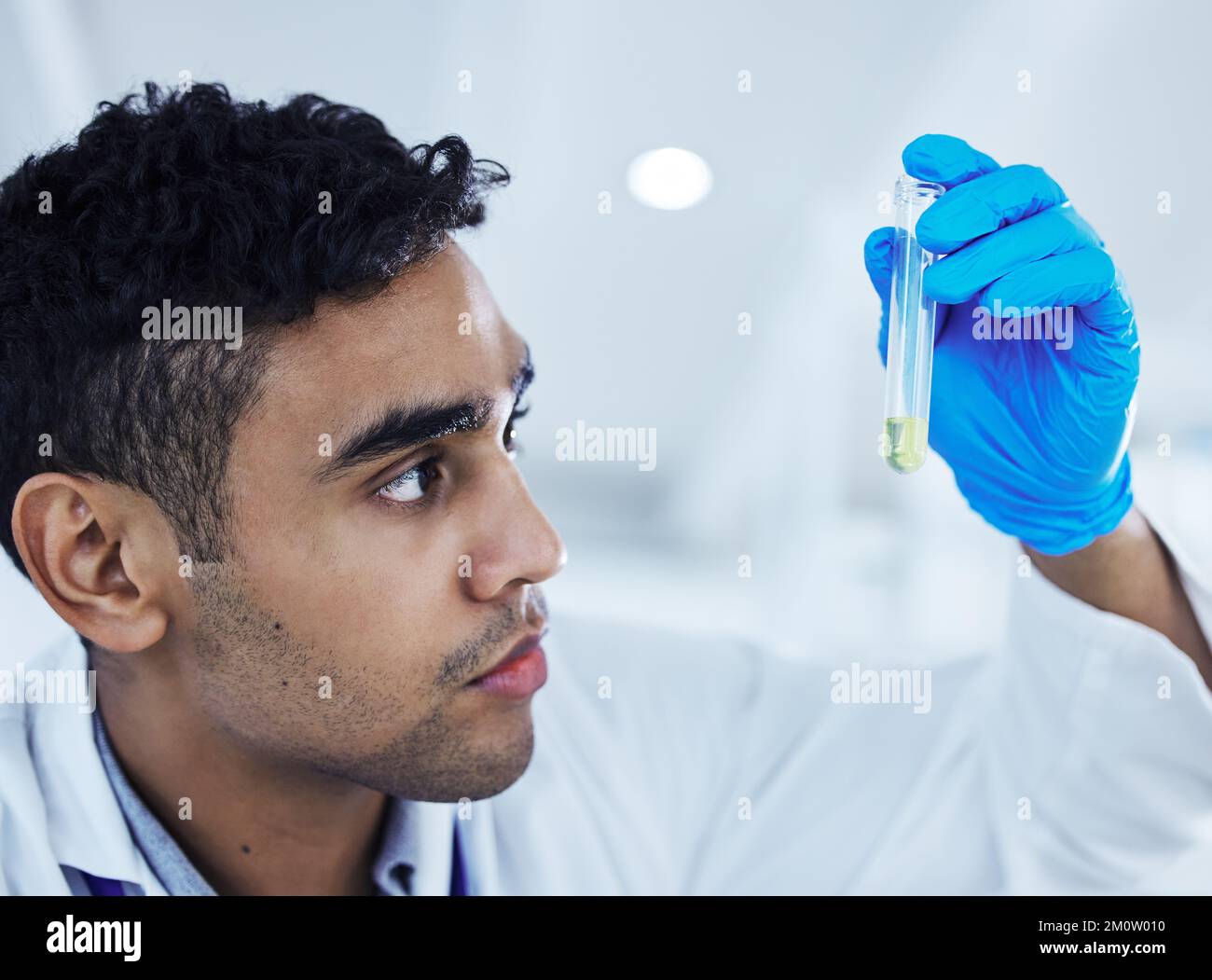 Non perde tempo. un giovane scienziato maschile che analizza una provetta. Foto Stock