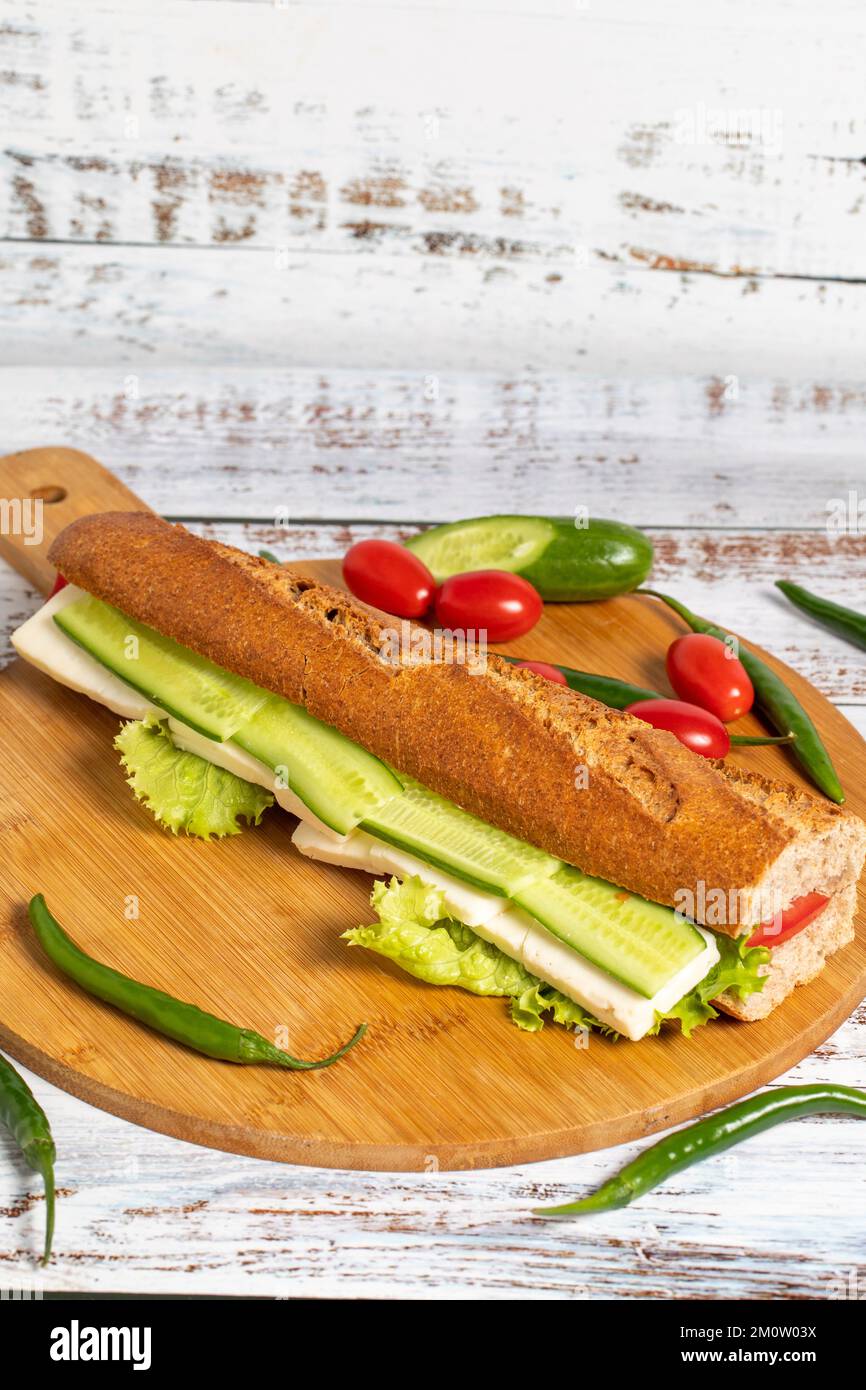 Sandwich baguette. Sandwich con olive, lattuga, pomodoro, cetriolo, cedro e feta su fondo ligneo Foto Stock