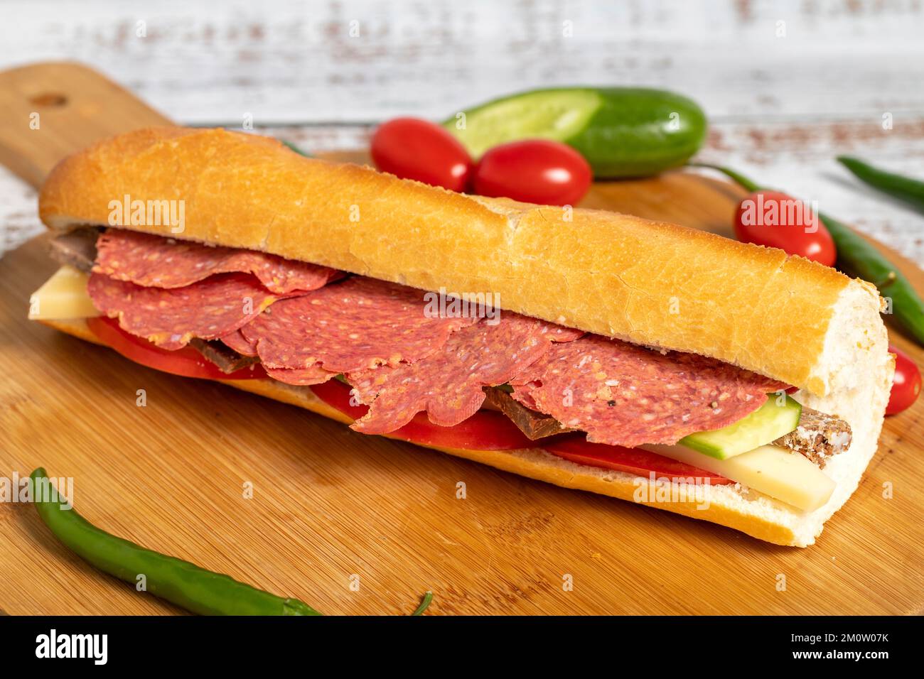 Sandwich baguette. Sandwich con salame, roast beef, cedro, pomodoro e cetriolo su sfondo ligneo Foto Stock