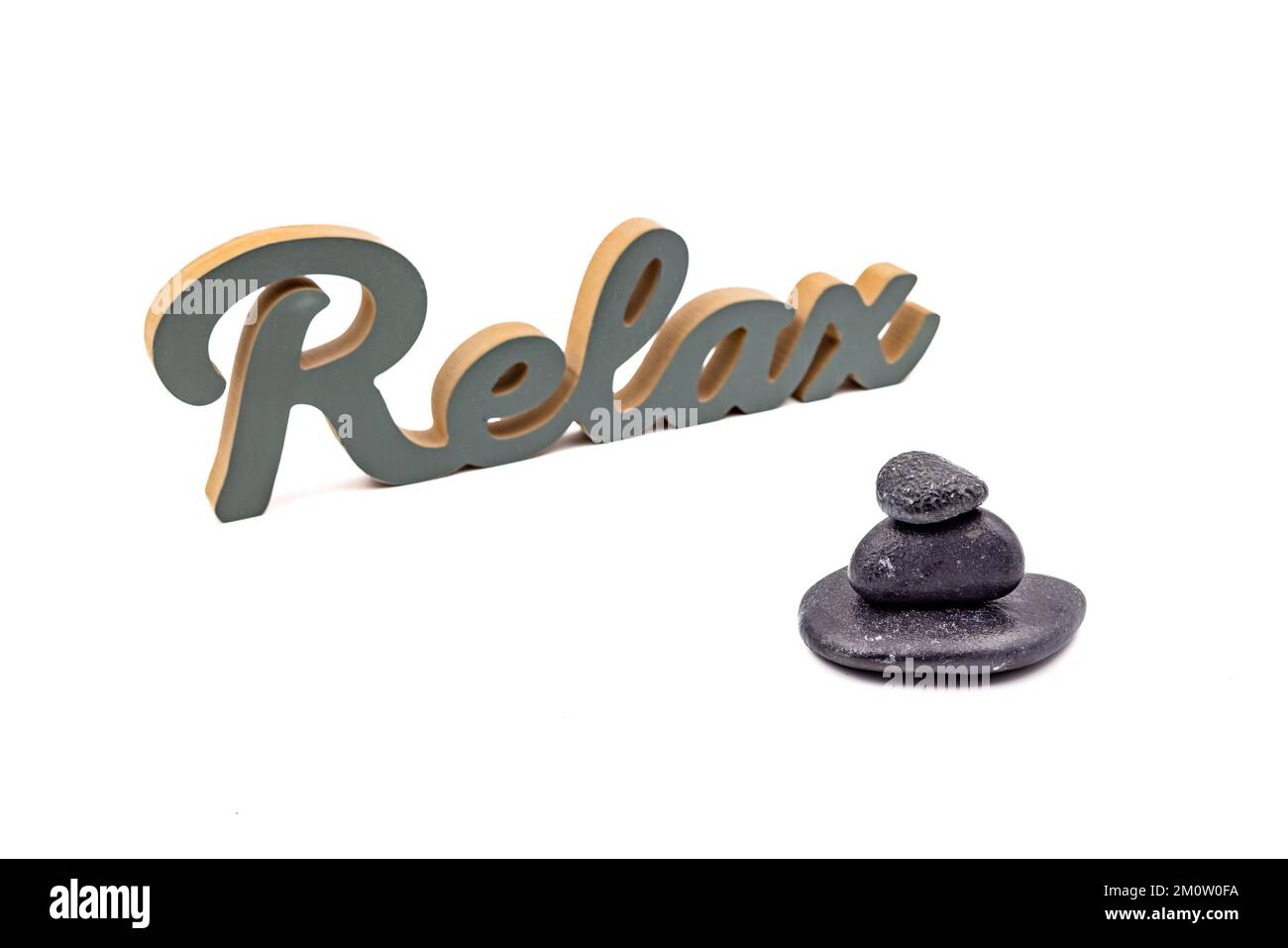 La scritta relax e un cairn nero isolato su uno sfondo bianco in studio vi invitano a rilassarvi Foto Stock