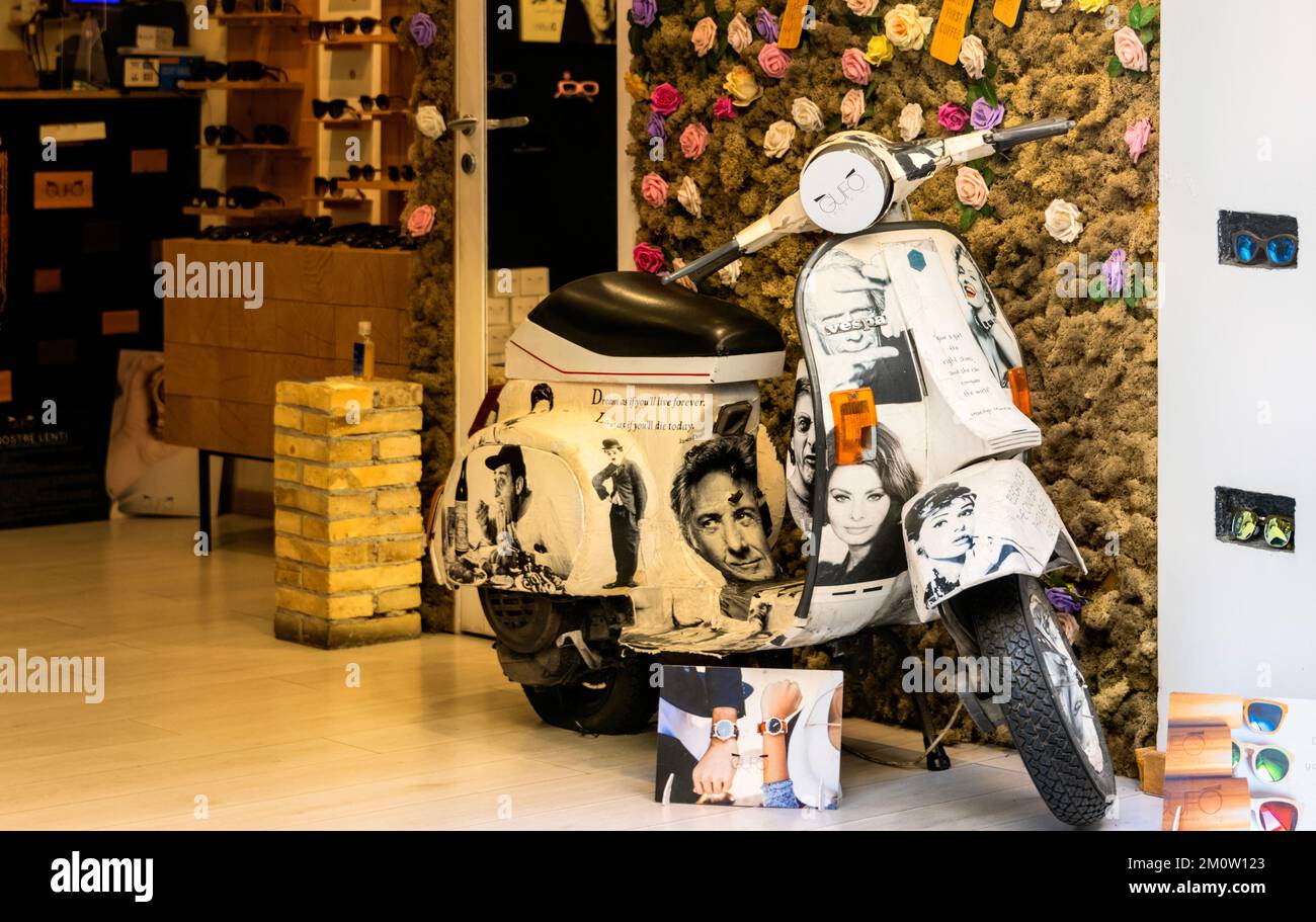 Old Vespa Scooter con le immagini di Sophia Loren e di altre persone famose dipinte su di esso, all'ingresso del negozio ottico, Taormina, Sicilia, Italia Foto Stock