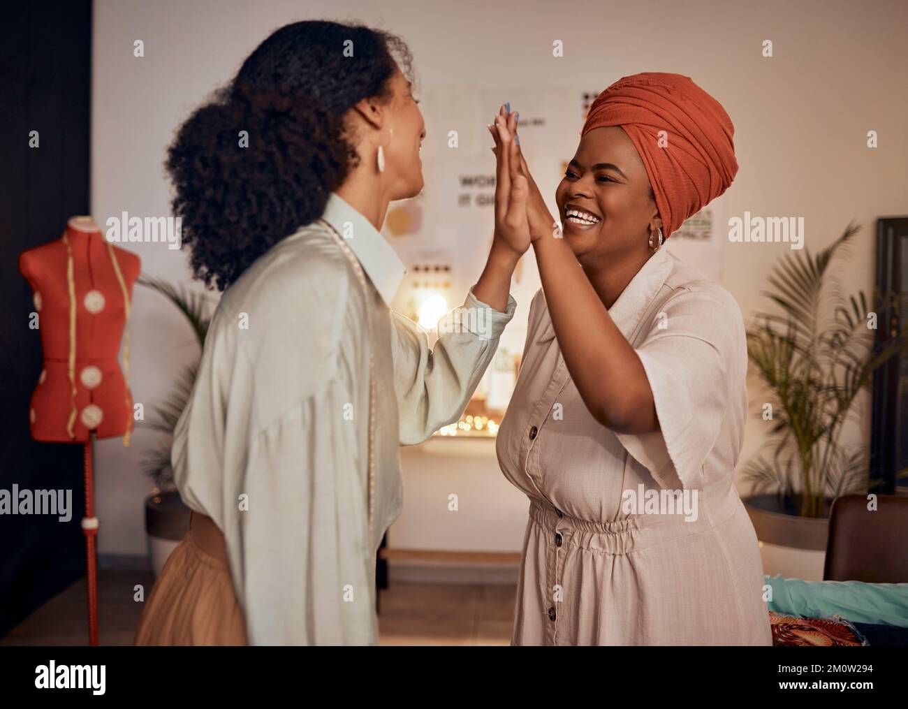 Moda, designer team e high five per il successo di design di stile o abbigliamento in uno studio di design. Donne nere, lavoro di squadra e mani alla moda Foto Stock