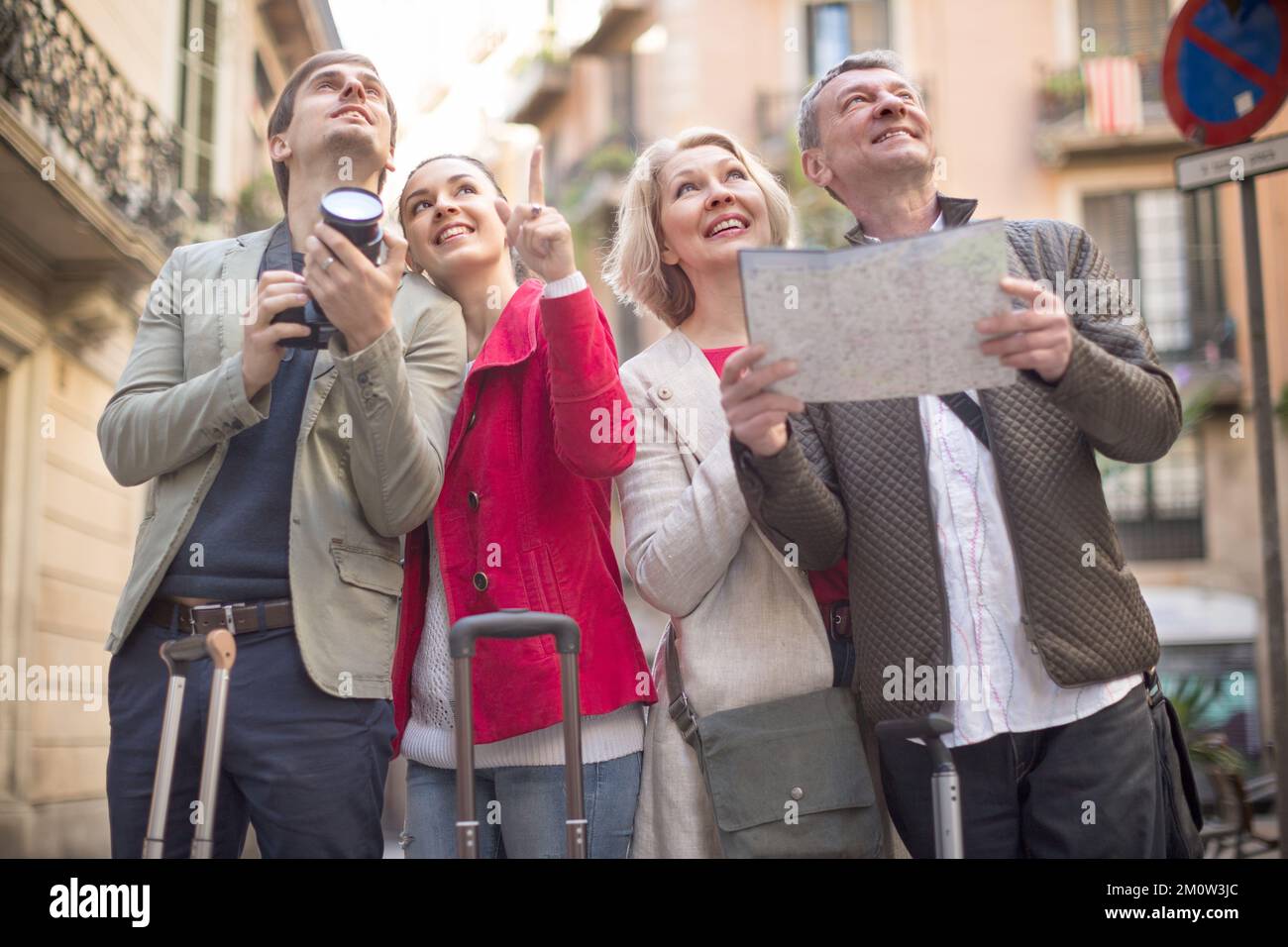 I turisti con valigie e macchina fotografica camminano lungo le strade storiche della città europea Foto Stock