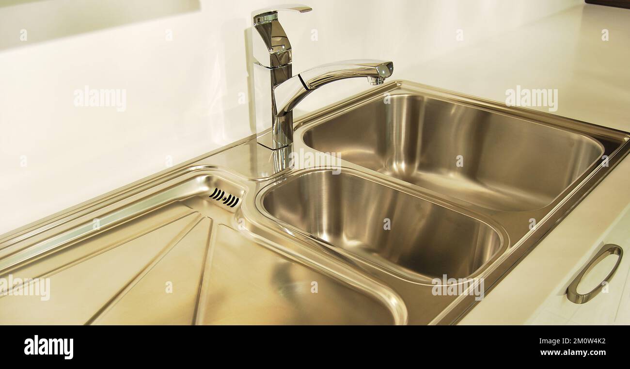 Interno di lussuosa cucina moderna e lavandino, rubinetto e scarico in acciaio inossidabile Foto Stock