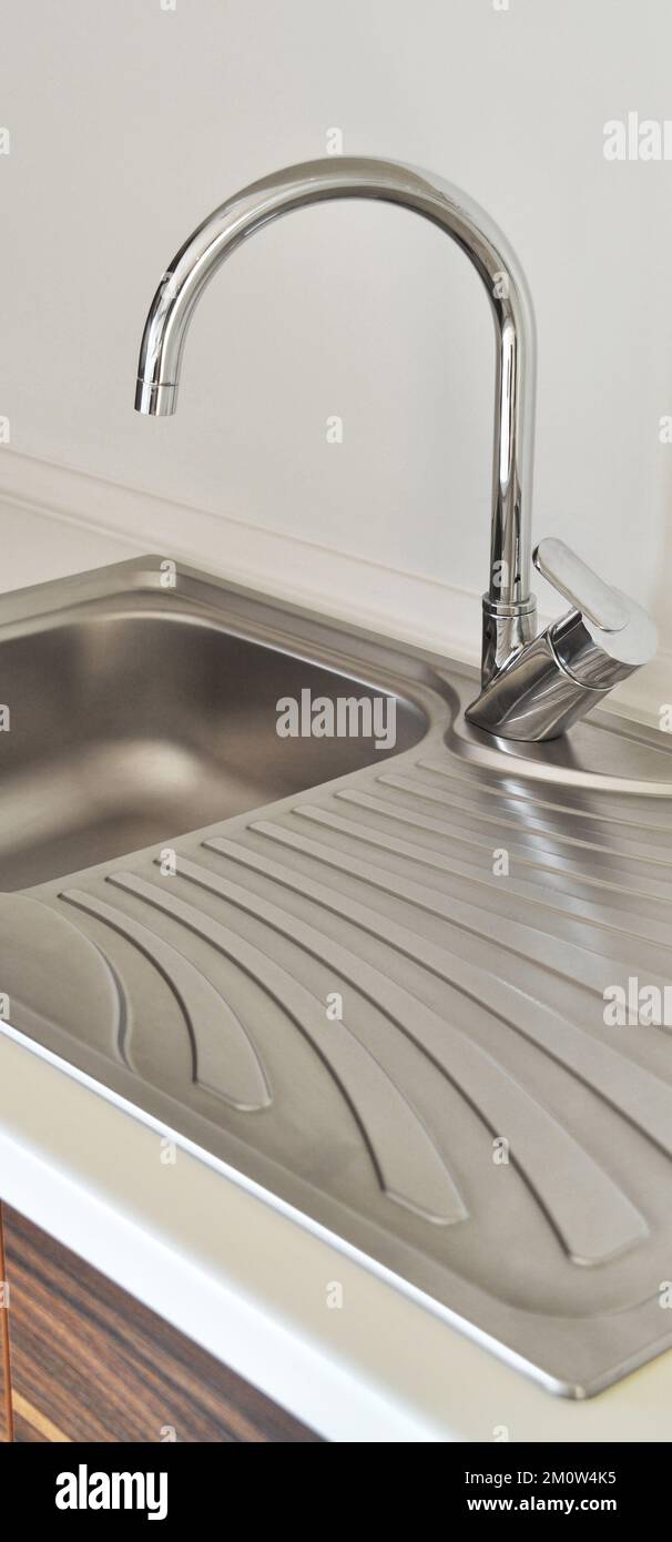 Interno di lussuosa cucina moderna e lavandino, rubinetto e scarico in acciaio inossidabile Foto Stock