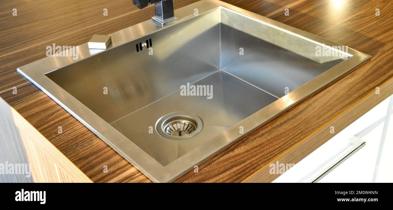 Interno di lussuosa cucina moderna e lavandino, rubinetto e scarico in acciaio inossidabile Foto Stock