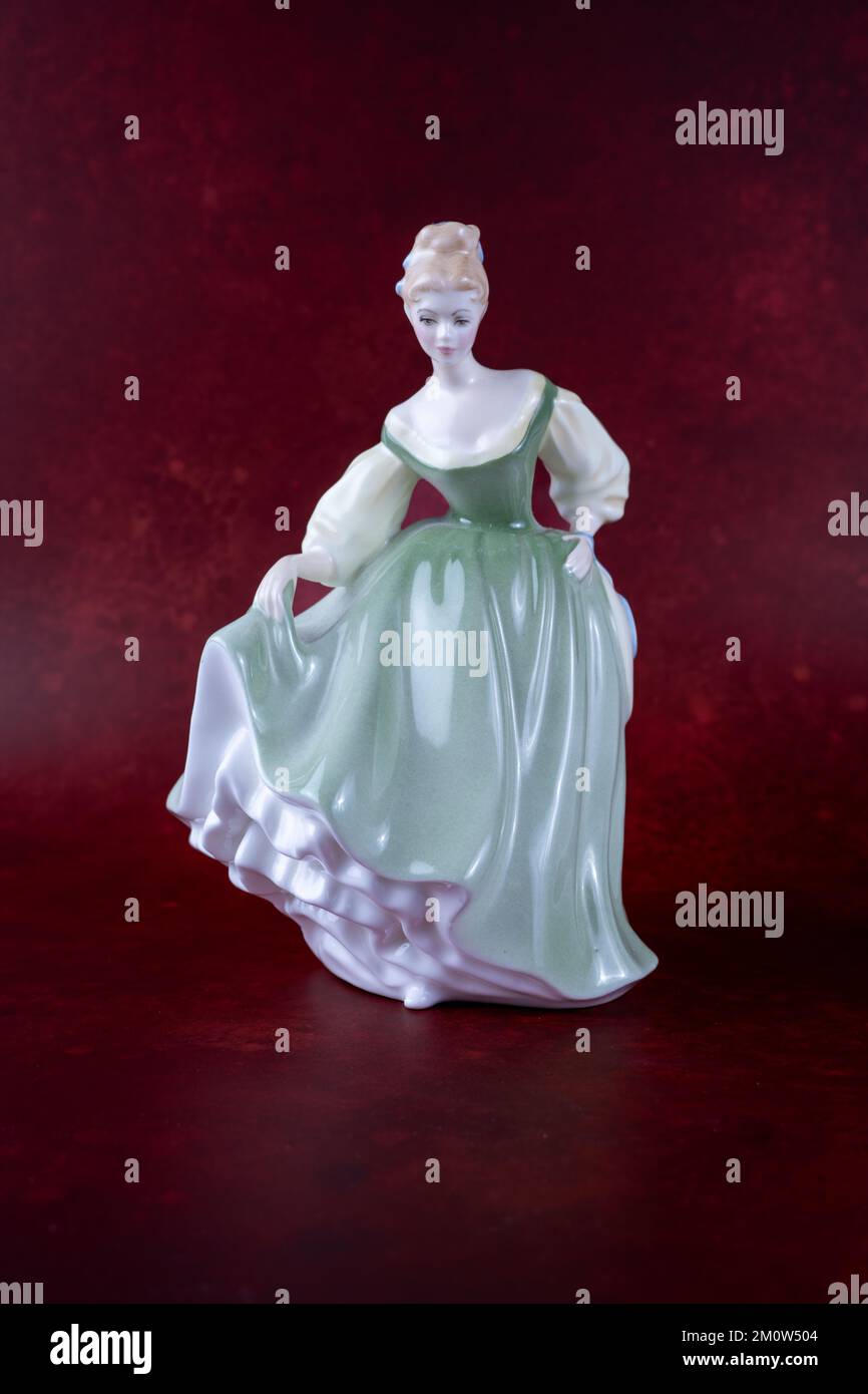 Bone Cina Donna figurina indossando un vestito verde isolato su uno sfondo rosso scuro Foto Stock