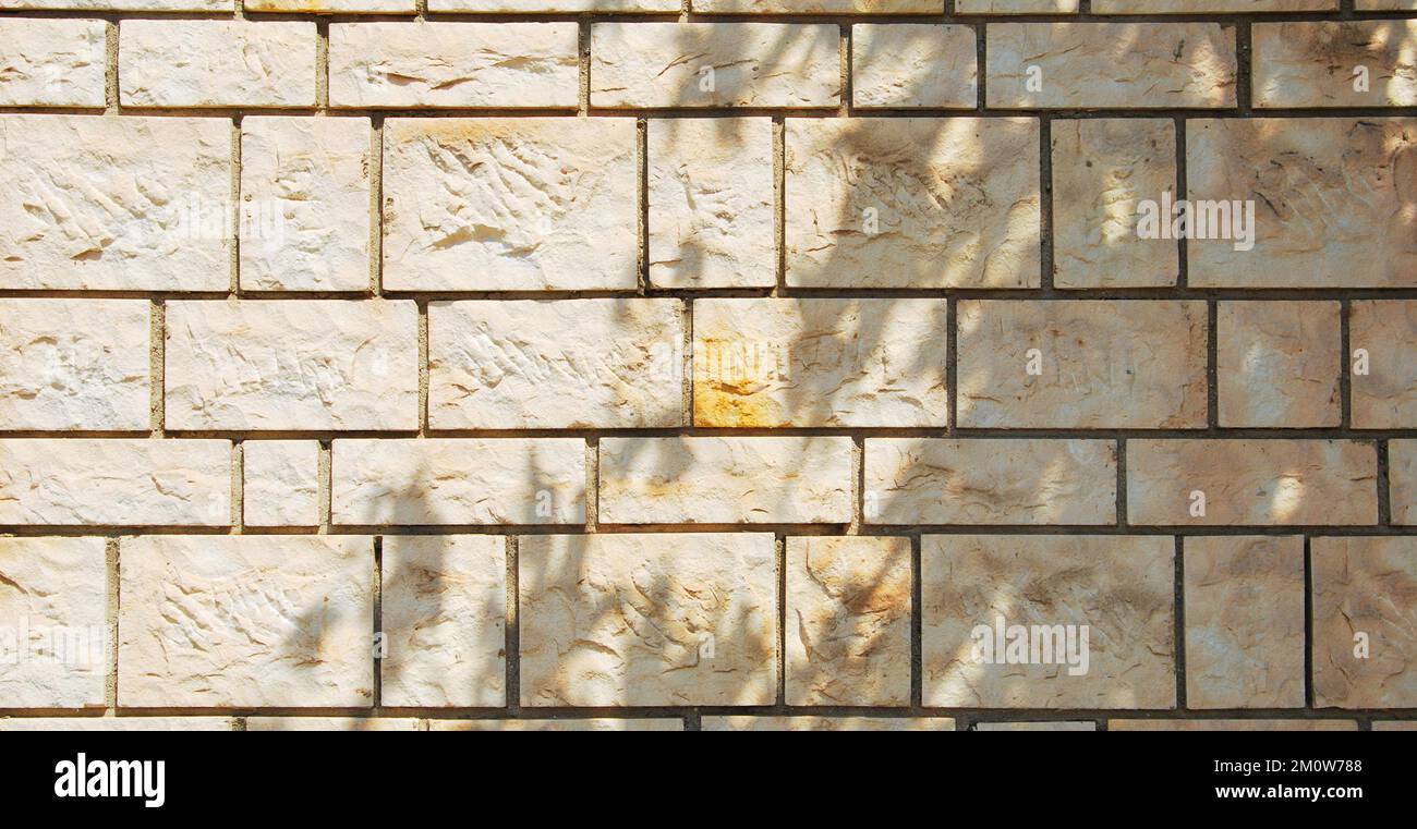 Robusto muro in pietra con taglio giallo e beige, ideale per sfondi, senza cuciture allineate Foto Stock