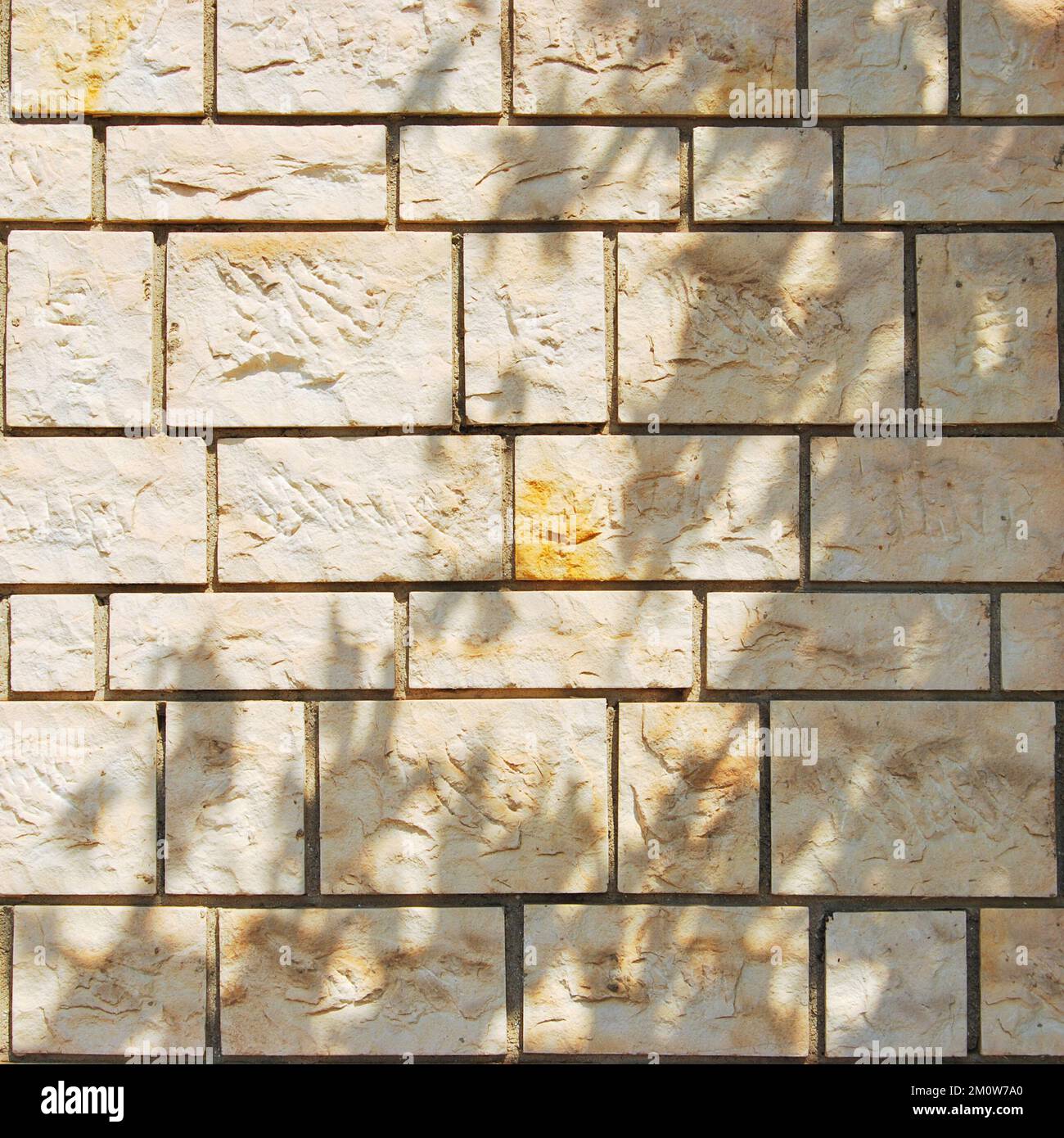 Robusto muro in pietra con taglio giallo e beige, ideale per sfondi, senza cuciture allineate Foto Stock