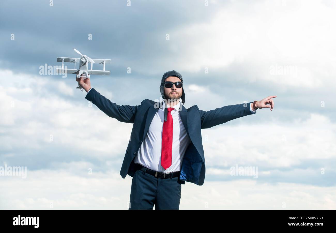 uomo d'affari in tuta e cappello pilota lancio aereo giocattolo su sfondo cielo. sfida Foto Stock