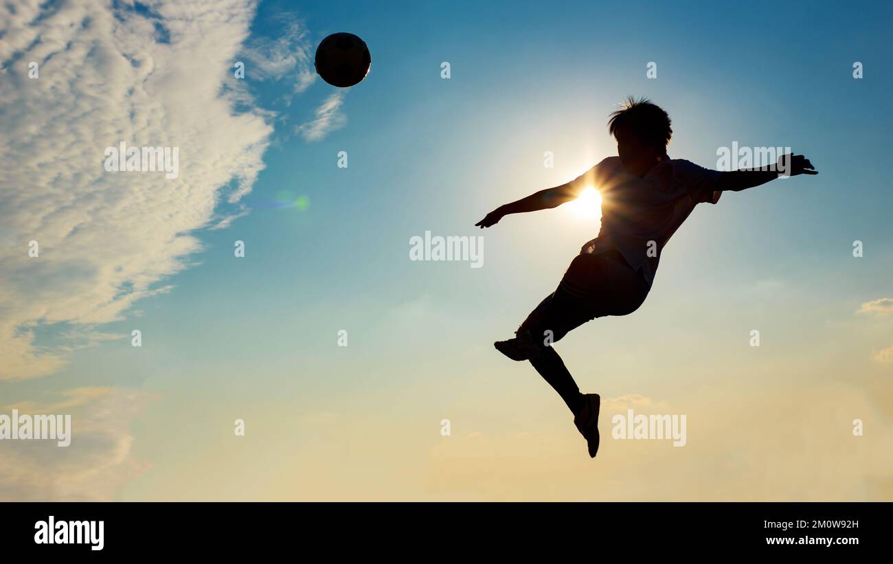 Silhouette sport d'azione all'aperto dei giocatori di calcio sul cielo tramonto. Atleta uomo jumping calcio palla per sfondo torneo di coppa del mondo. Foto Stock