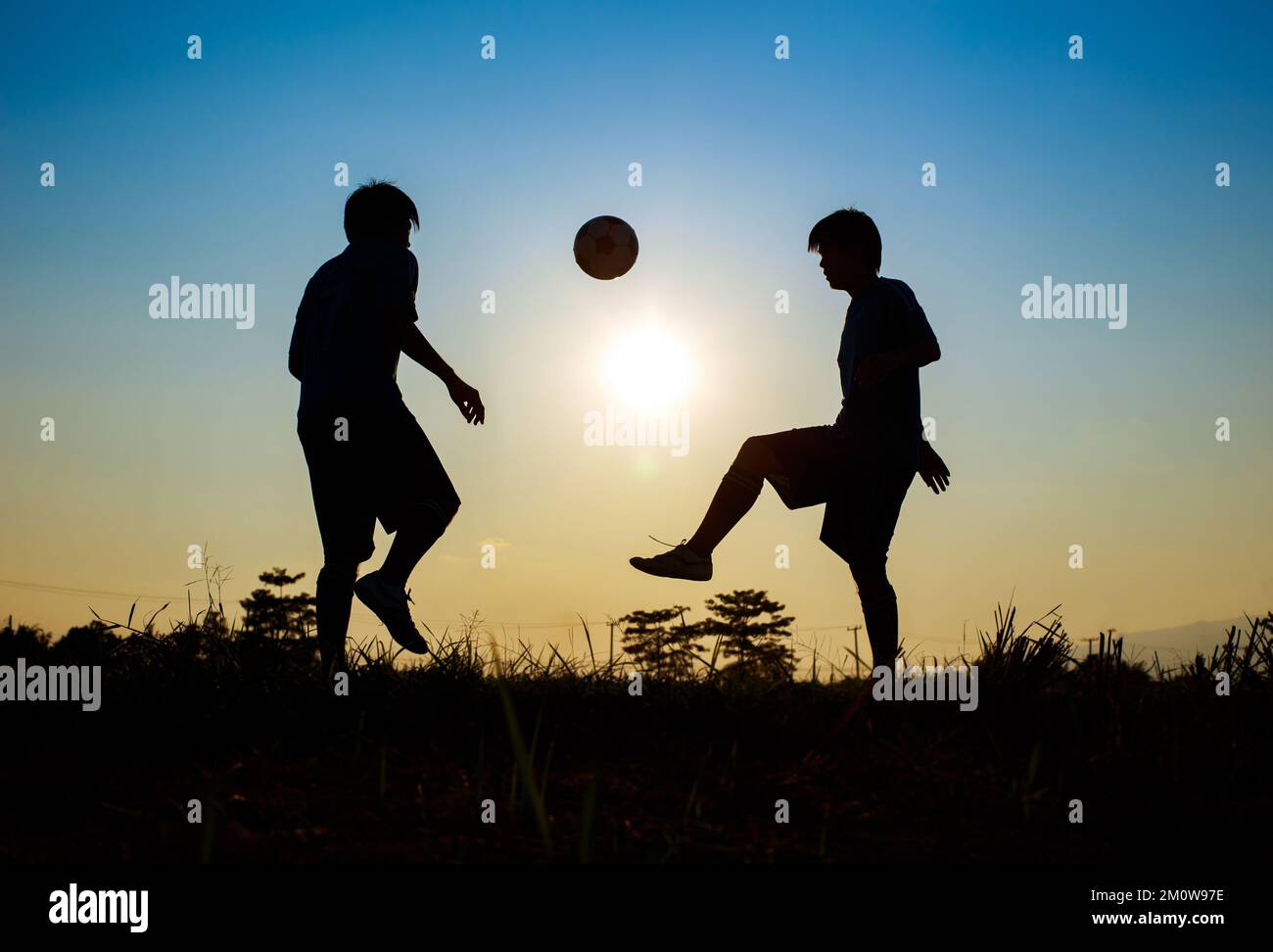 Silhouette sport d'azione all'aperto dei giocatori di calcio sul cielo tramonto. Atleta uomo jumping calcio palla per sfondo torneo di coppa del mondo. Foto Stock