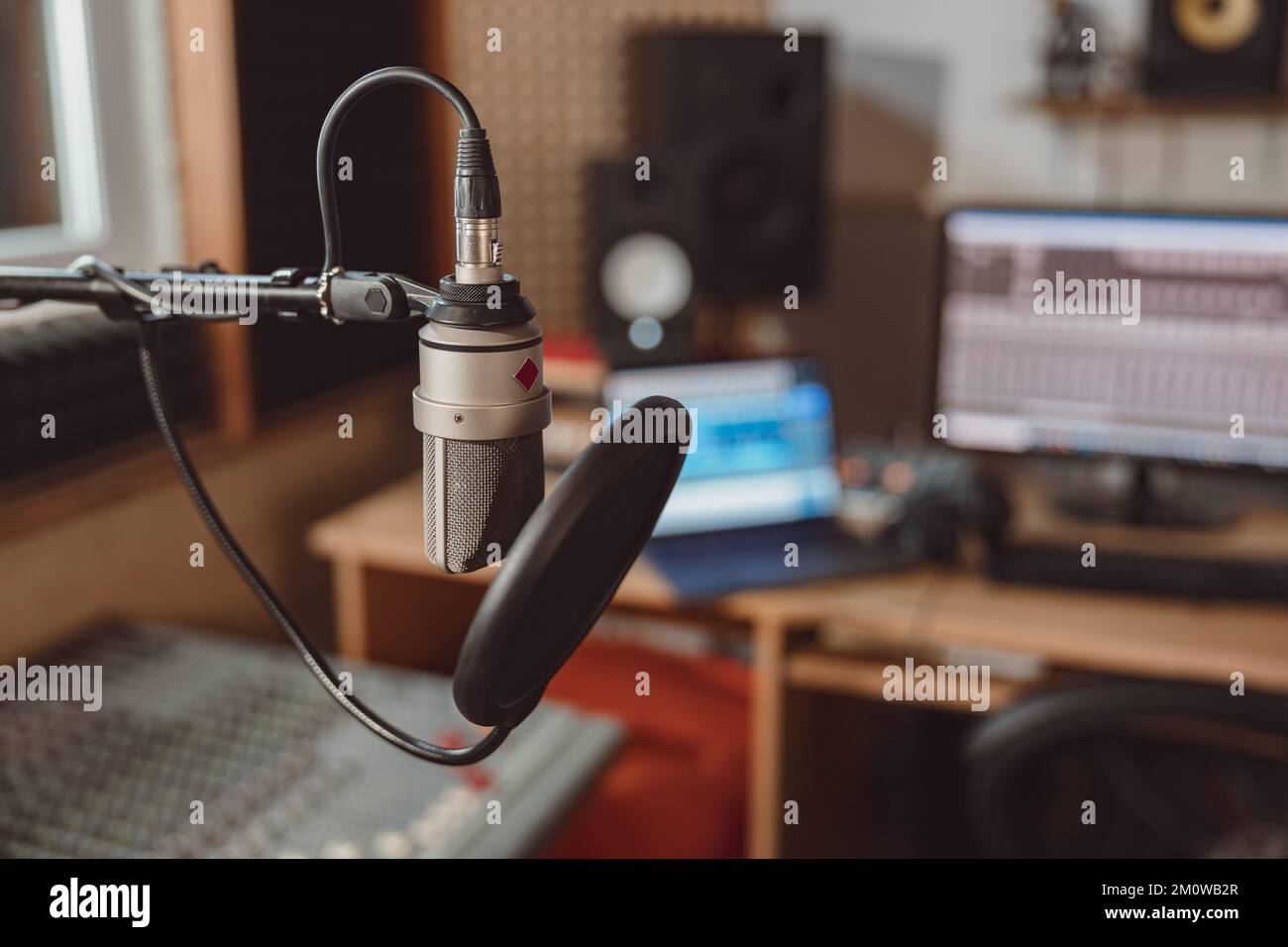 Concentratevi su un microfono professionale sul luogo di lavoro sfocato di un ingegnere del suono in uno studio di registrazione musicale Foto Stock