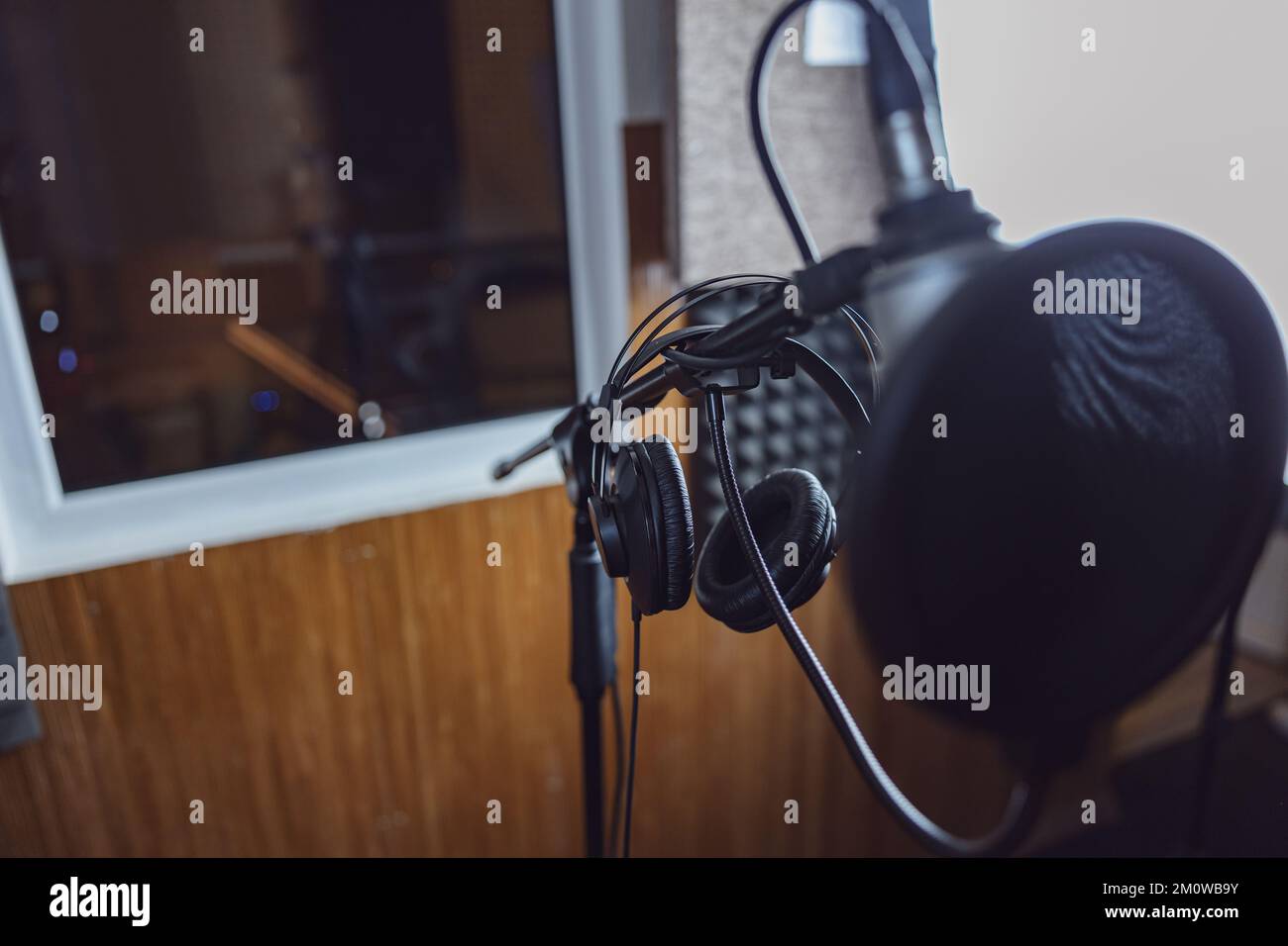 Guarda attraverso il microfono e le cuffie professionali fino alla finestra con stanza insonorizzata nello studio di registrazione e trasmissione Foto Stock