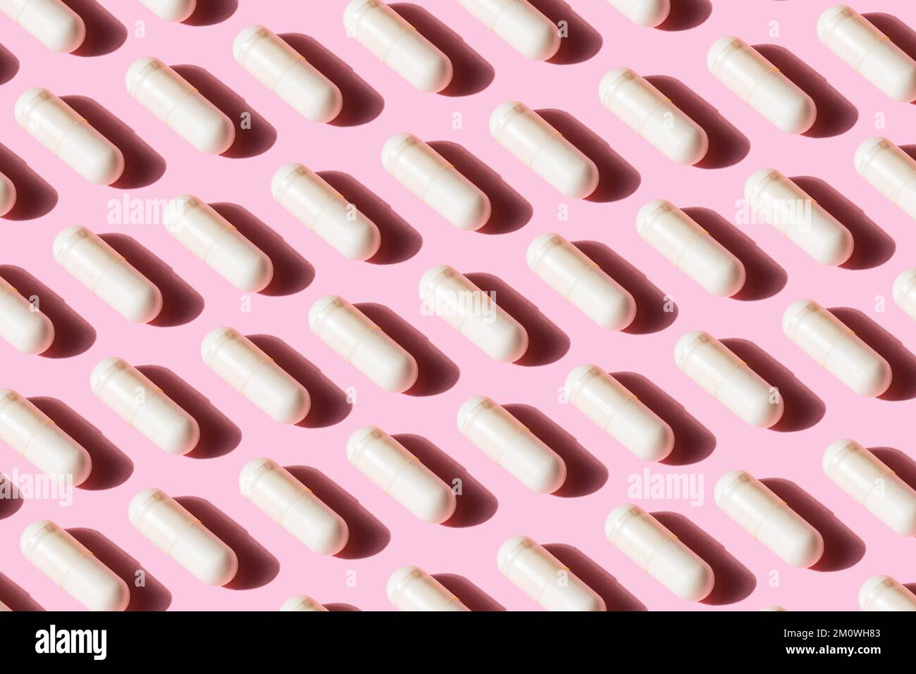 Un modello di fila capsula bianca pillola isolato su sfondo rosa, concetto medico di alimentazione sana Foto Stock