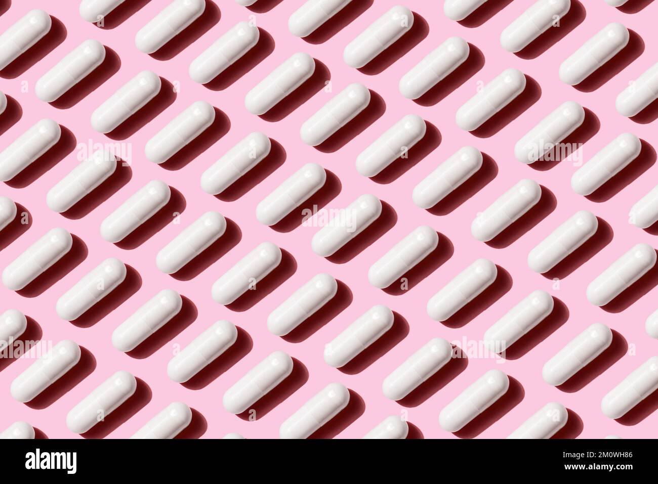 Un modello di fila capsula bianca pillola isolato su sfondo rosa, concetto medico di alimentazione sana Foto Stock