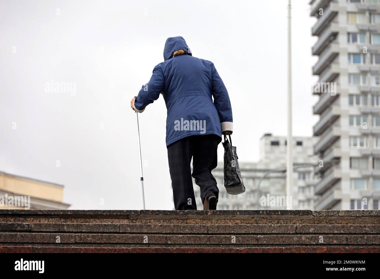 Vecchia donna con canne a piedi che sale le scale sulla strada cittadina. Concetto per disabilità, adulta limping, malattie della colonna vertebrale Foto Stock