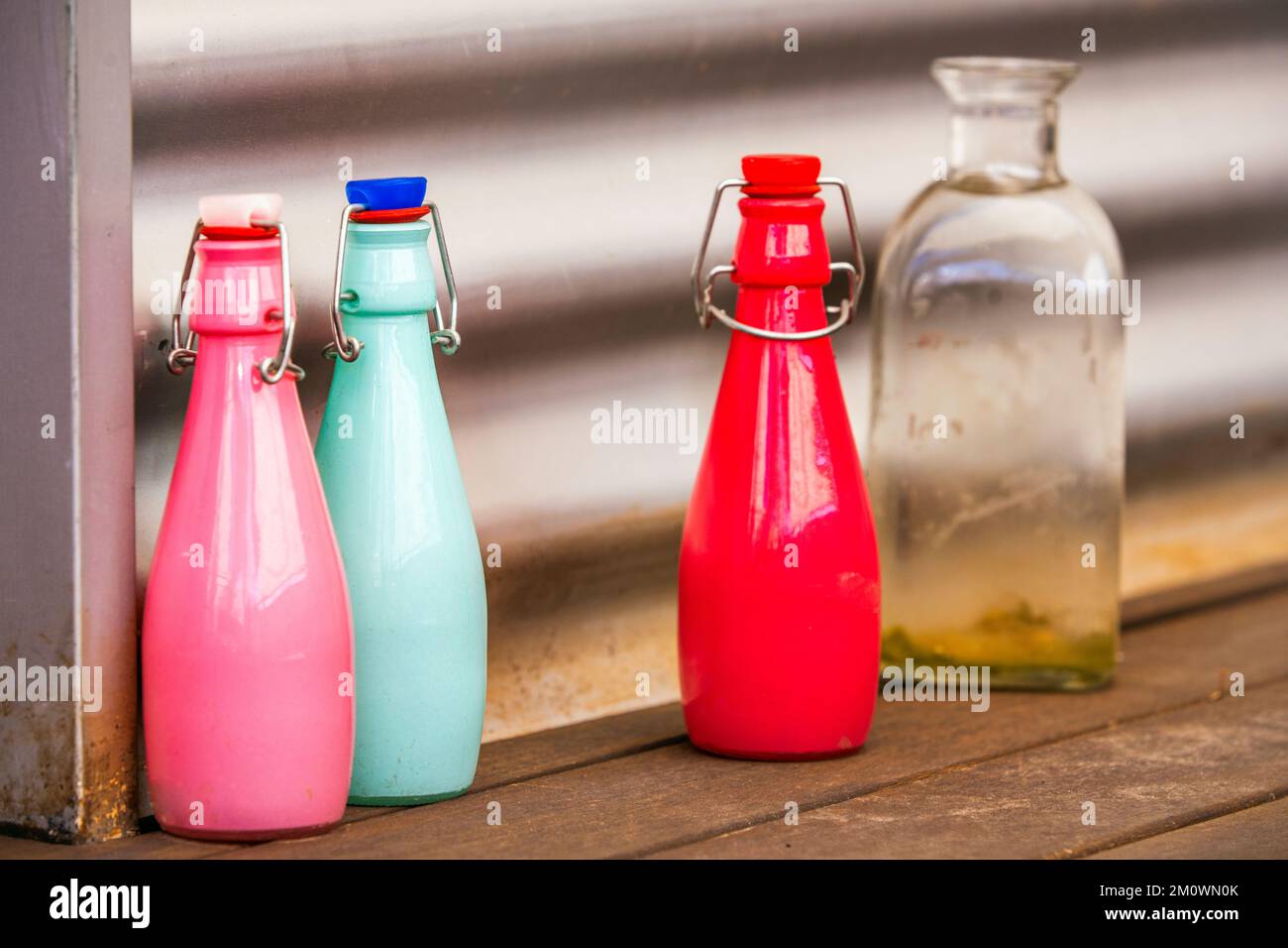 Bottiglie decorative in vetro di vari colori luminosi con tappi ermetici su  una superficie in legno Foto stock - Alamy