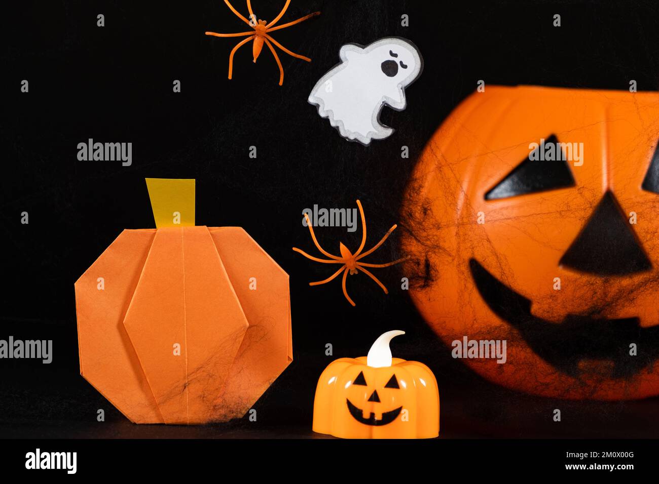 Zucche arancioni, un fantasma, ragni e ragnatele su uno sfondo nero, una celebrazione di Halloween. Foto Stock