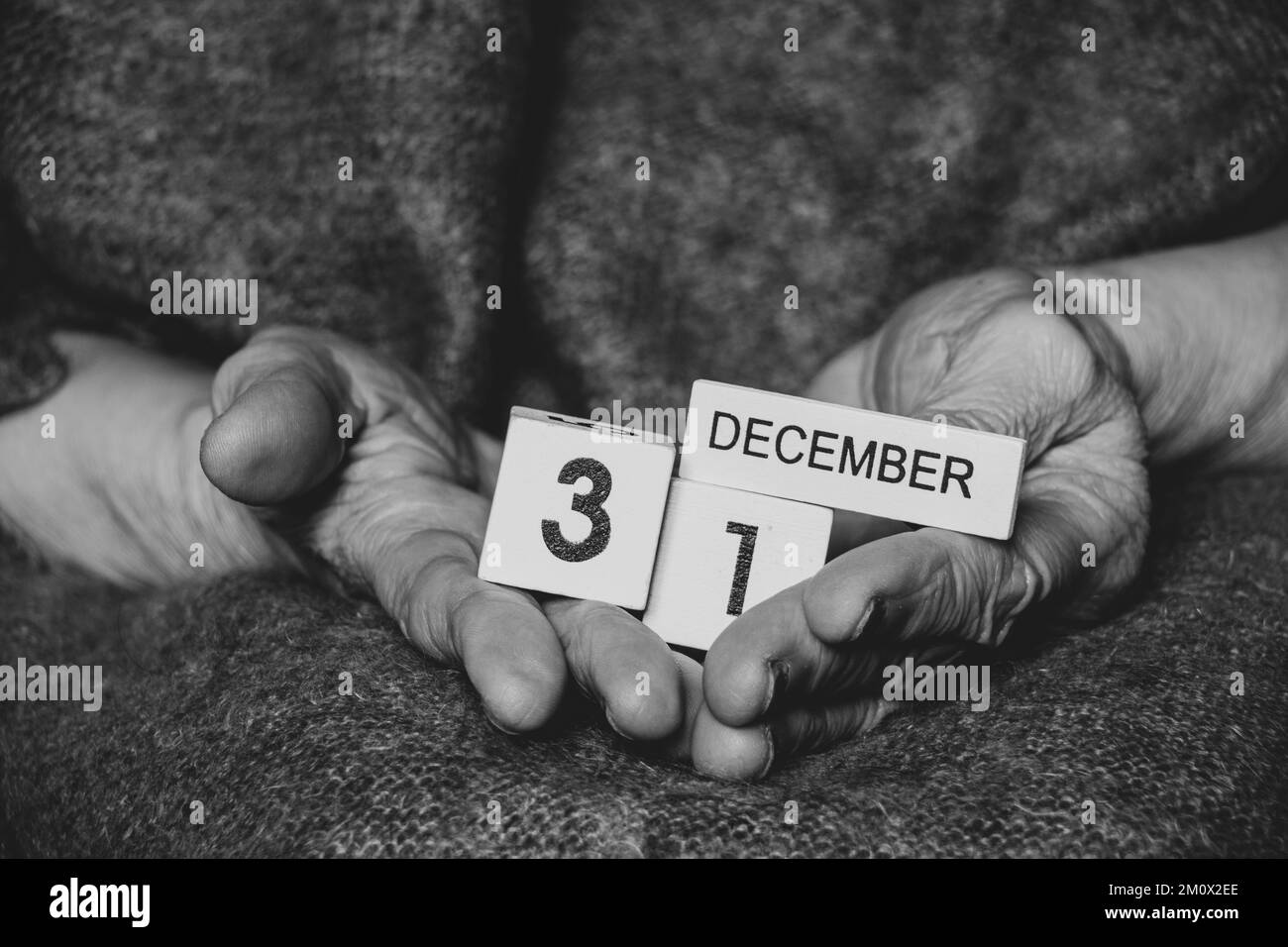 Dicembre 31 è scritto sui cubi che una vecchia donna tiene in mano, foto in bianco e nero, vacanza Foto Stock