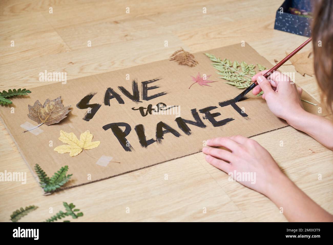 Donna irriconoscibile preparare un cartello con la citazione ecologica salvare il pianeta. Foto Stock