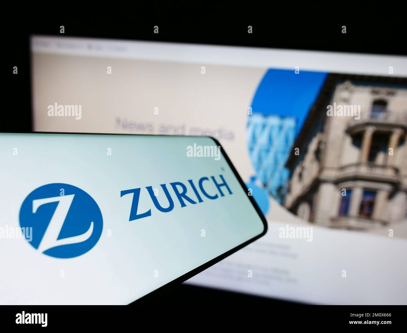 Smartphone con logo della società finanziaria svizzera Zurich Insurance Group AG sullo schermo di fronte al sito Web. Messa a fuoco al centro a sinistra del display del telefono. Foto Stock