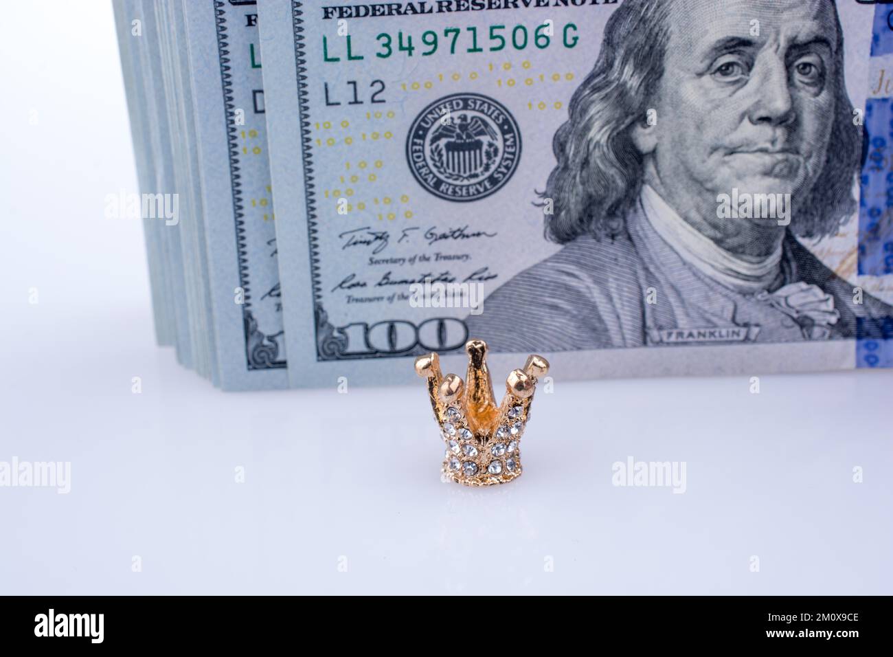Banconote americane da 100 dollari e una corona color oro Foto Stock
