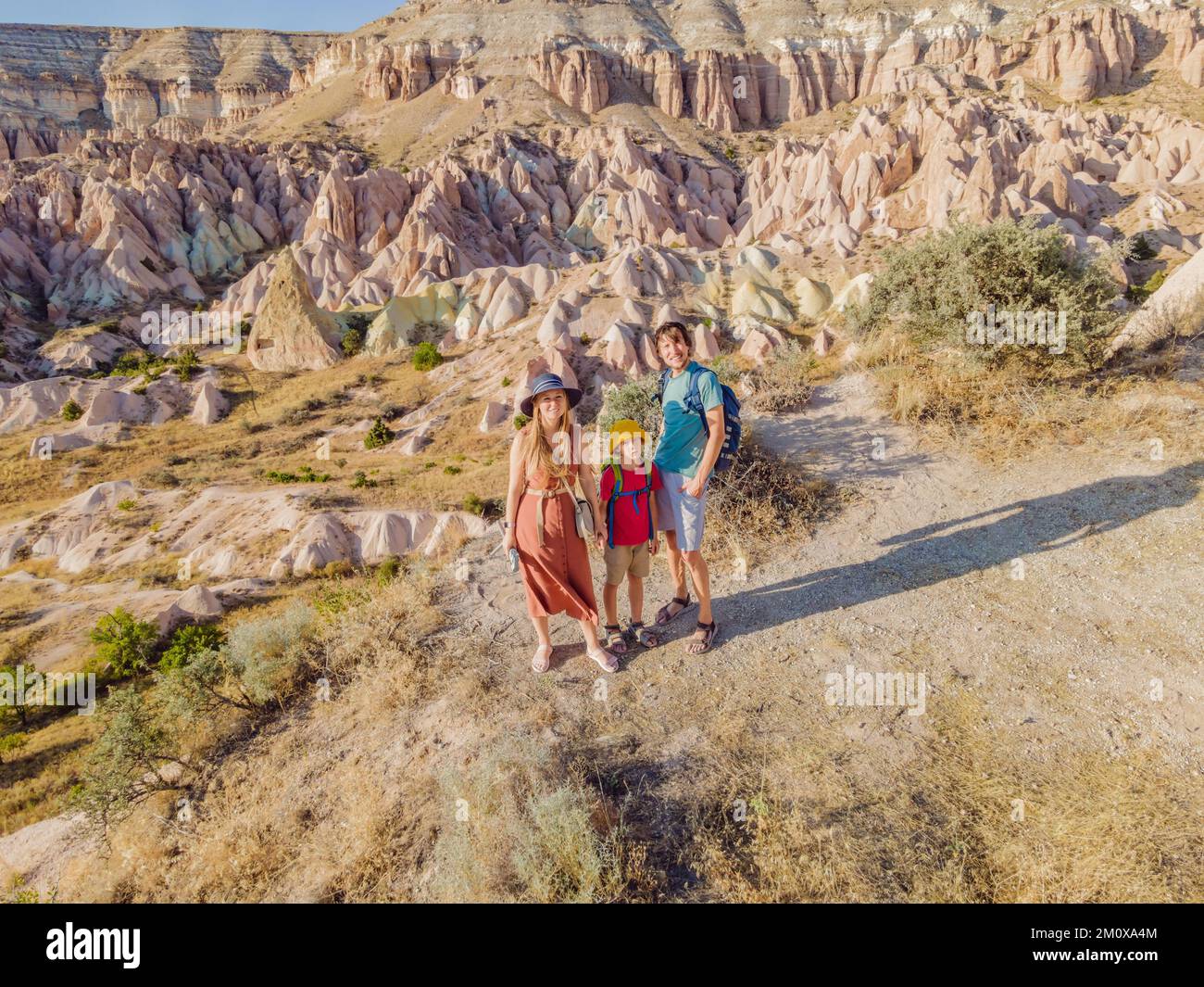 Famiglia felice madre, padre e figlio turisti esplorando la valle con formazioni rocciose e grotte delle fate vicino Goreme in Cappadocia Turchia Foto Stock