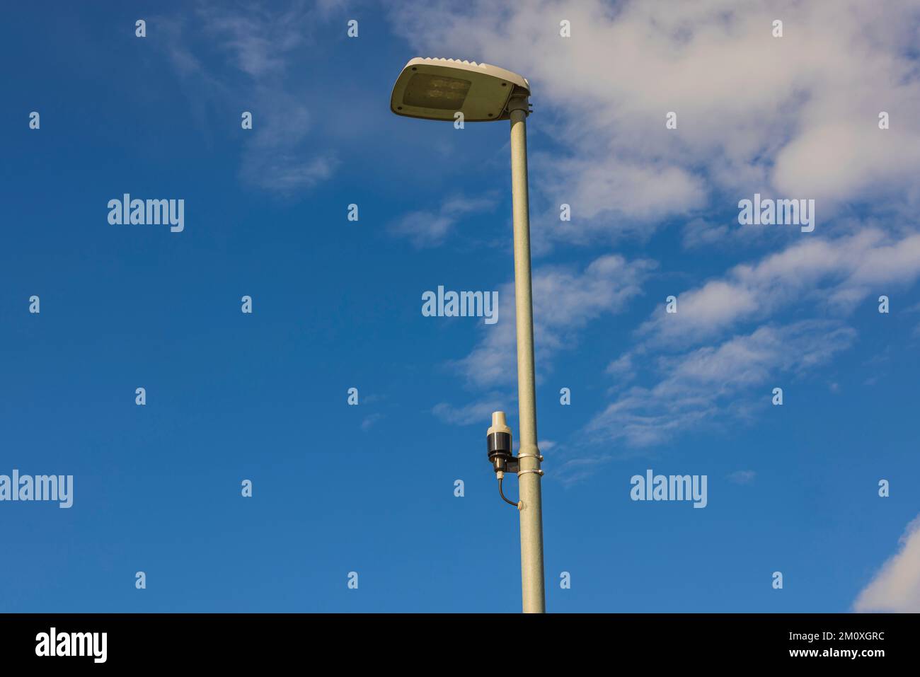 Tecnologia visione del sensore di luce su palo di illuminazione stradale su cielo blu con raro sfondo bianco nuvole. Svezia. Foto Stock