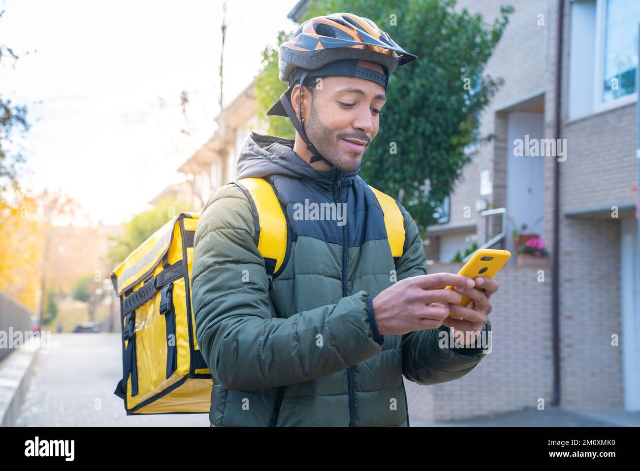 Concetto di consegna degli alimenti. Driver afro-americano con smartphone in stile zaino per la consegna dei prodotti Foto Stock