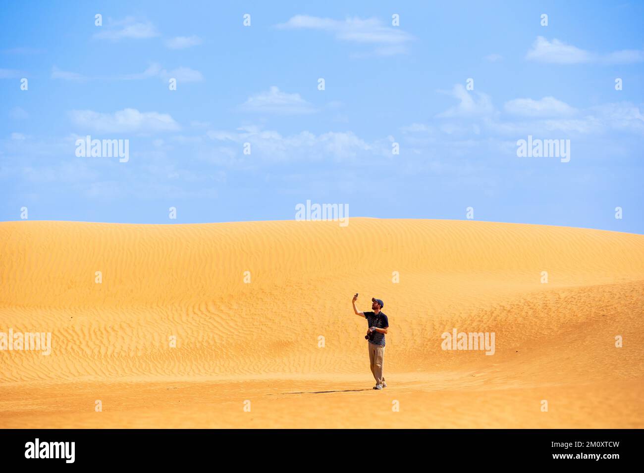 Un uomo guarda il suo telefono nella Dubai Desert Conservation Reserve. Foto Stock